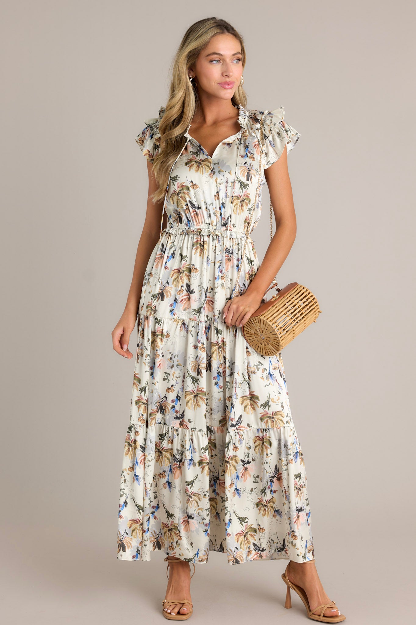 This ivory floral dress features a v-neckline, a self-tie drawstring, a floral pattern, a tiered design, tiered sleeves and a flowing silhouette.