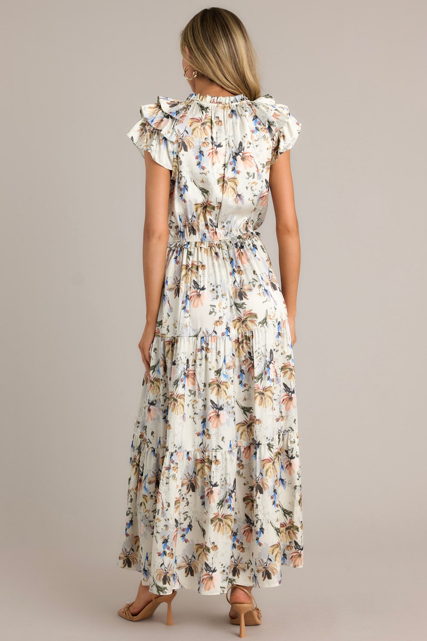 Back view of an ivory floral dress highlighting the overall fit, tiered design, and flowing silhouette.