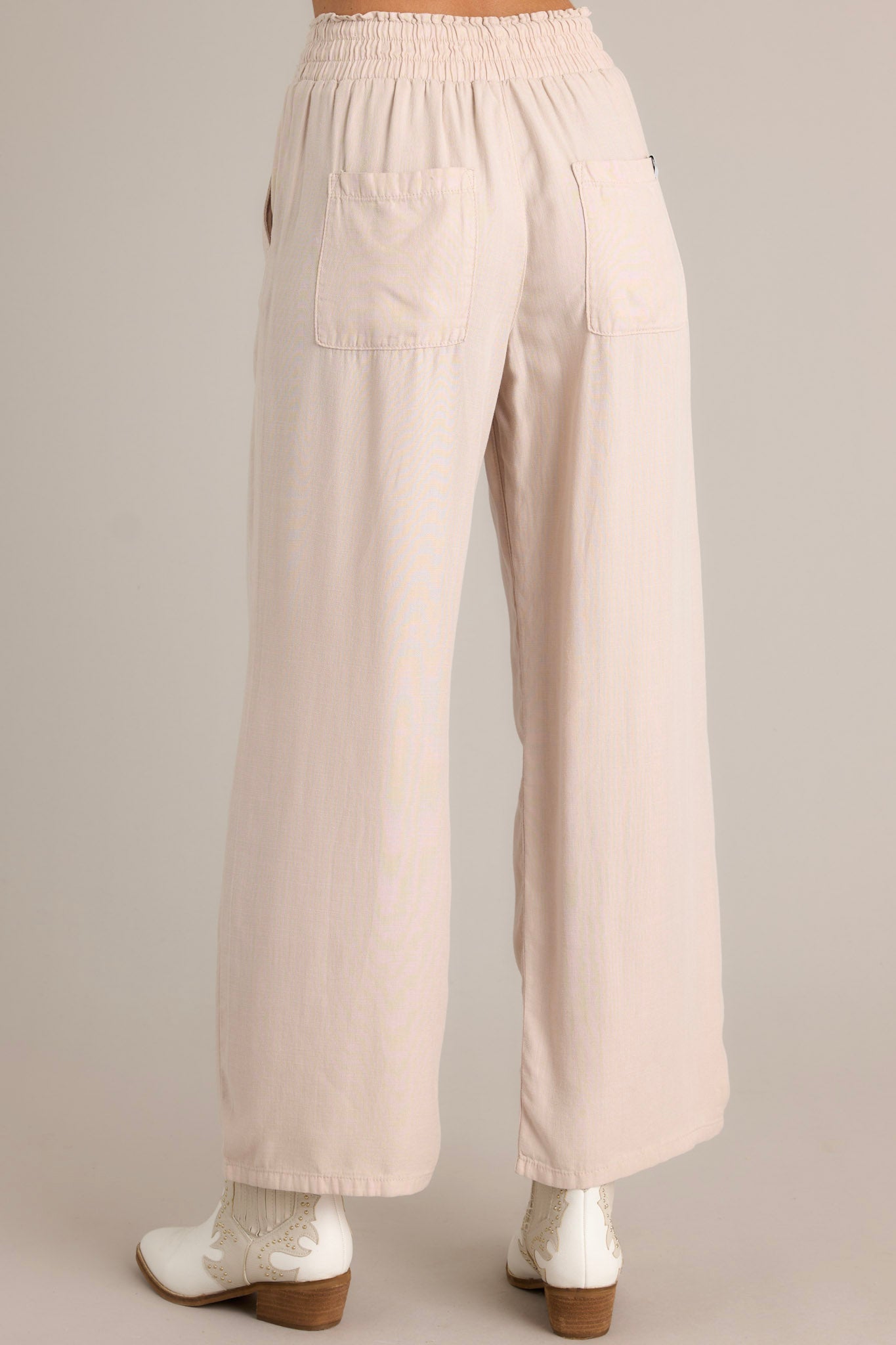 Back view of beige pants highlighting the elastic waistband, self-tie drawstring, and functional back pockets.