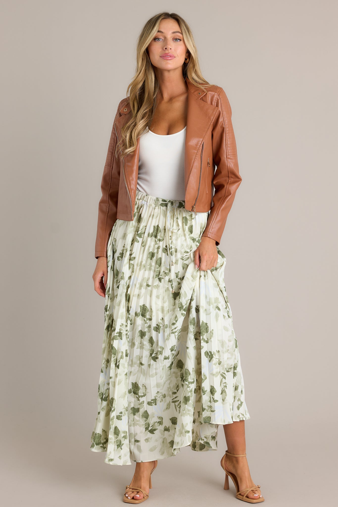 This green skirt features a high waisted design, an elastic waistband, a self-tie drawstring with bead detailing, pleats throughout, and a flowing silhouette.