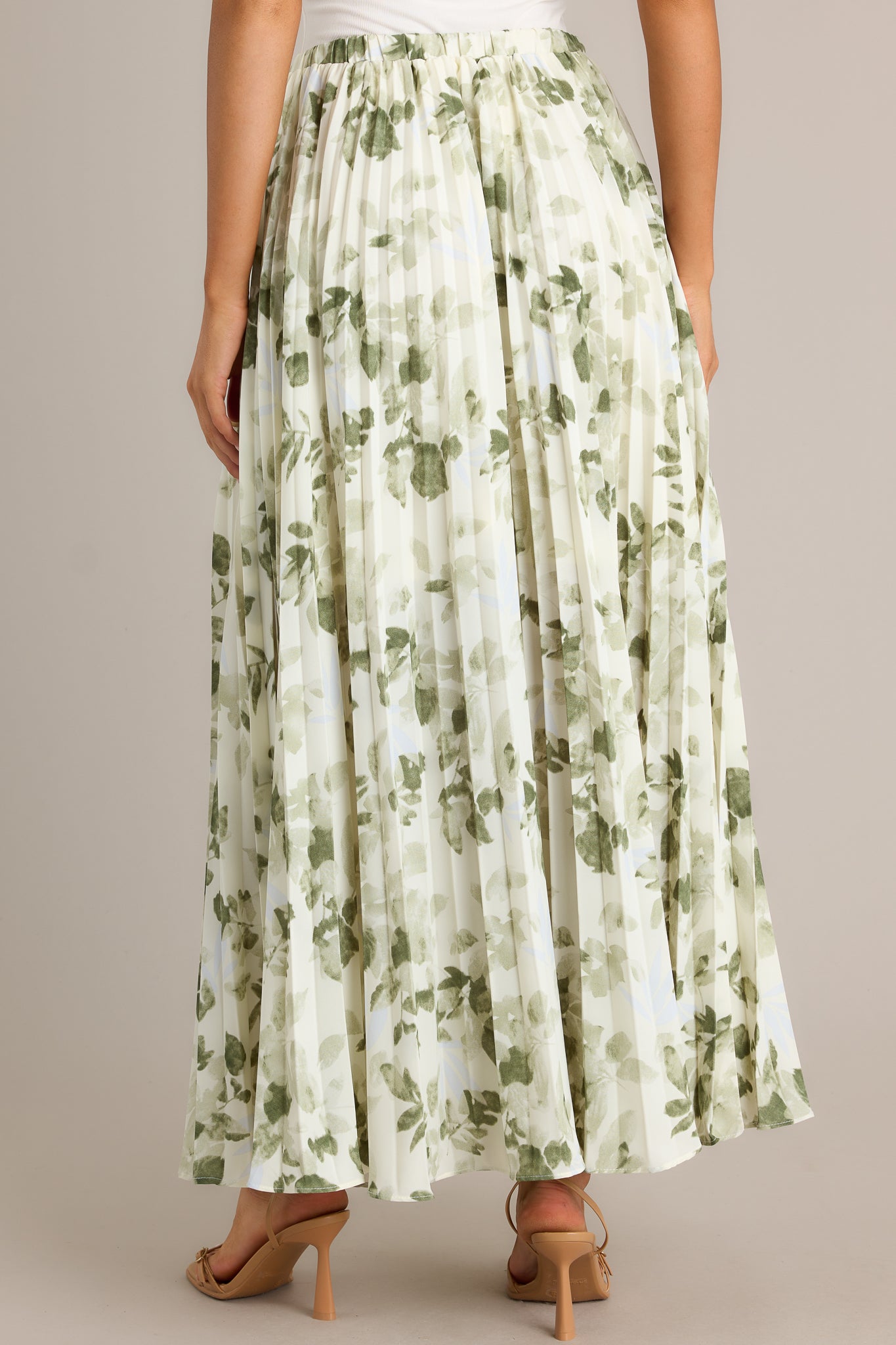 Back view of a green skirt showcasing the high waisted design, elastic waistband, and pleats throughout.