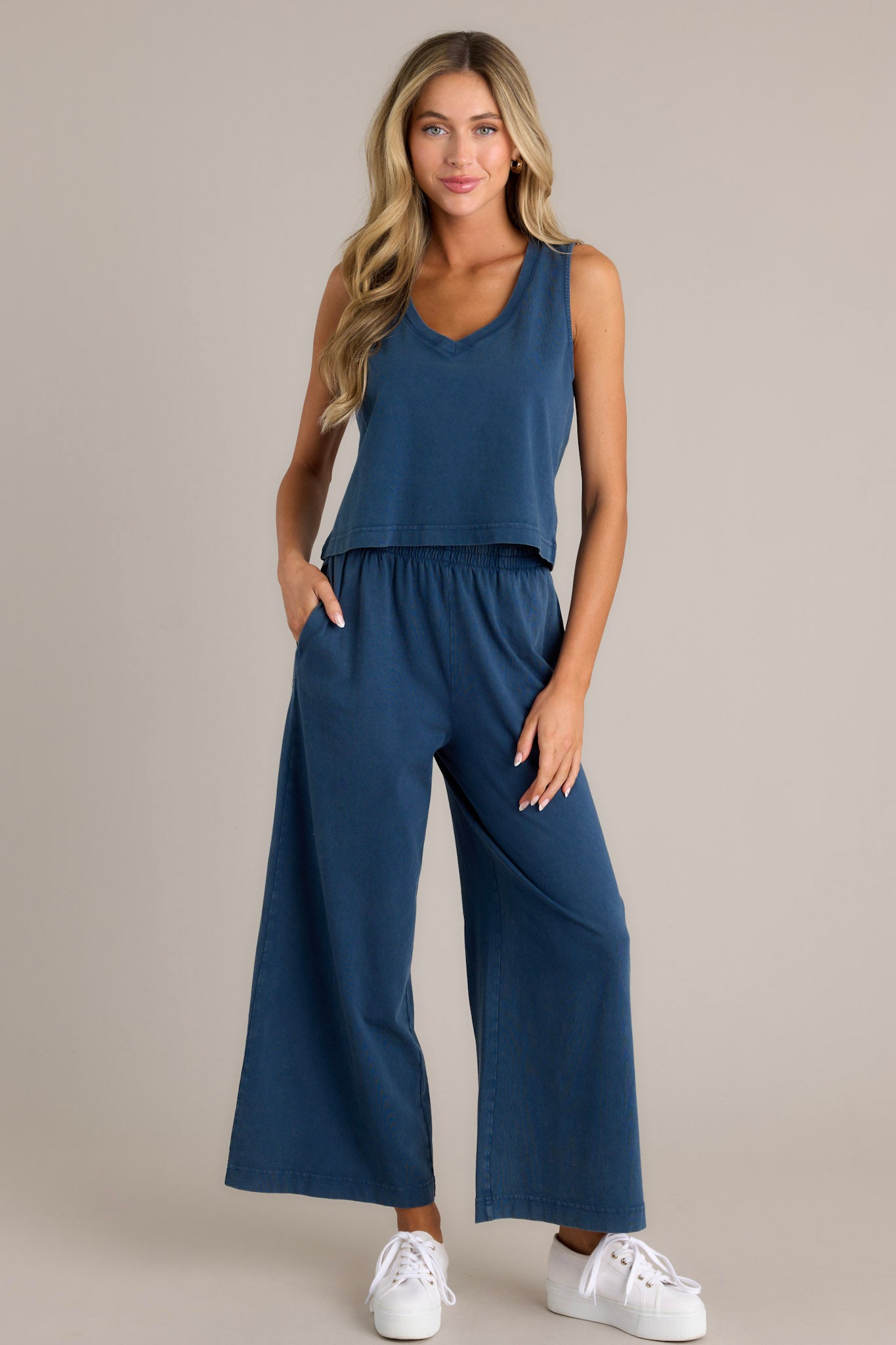 Full length view of blue flare pants with an elastic waistband, functional pockets, a wide leg design, and a soft jersey material