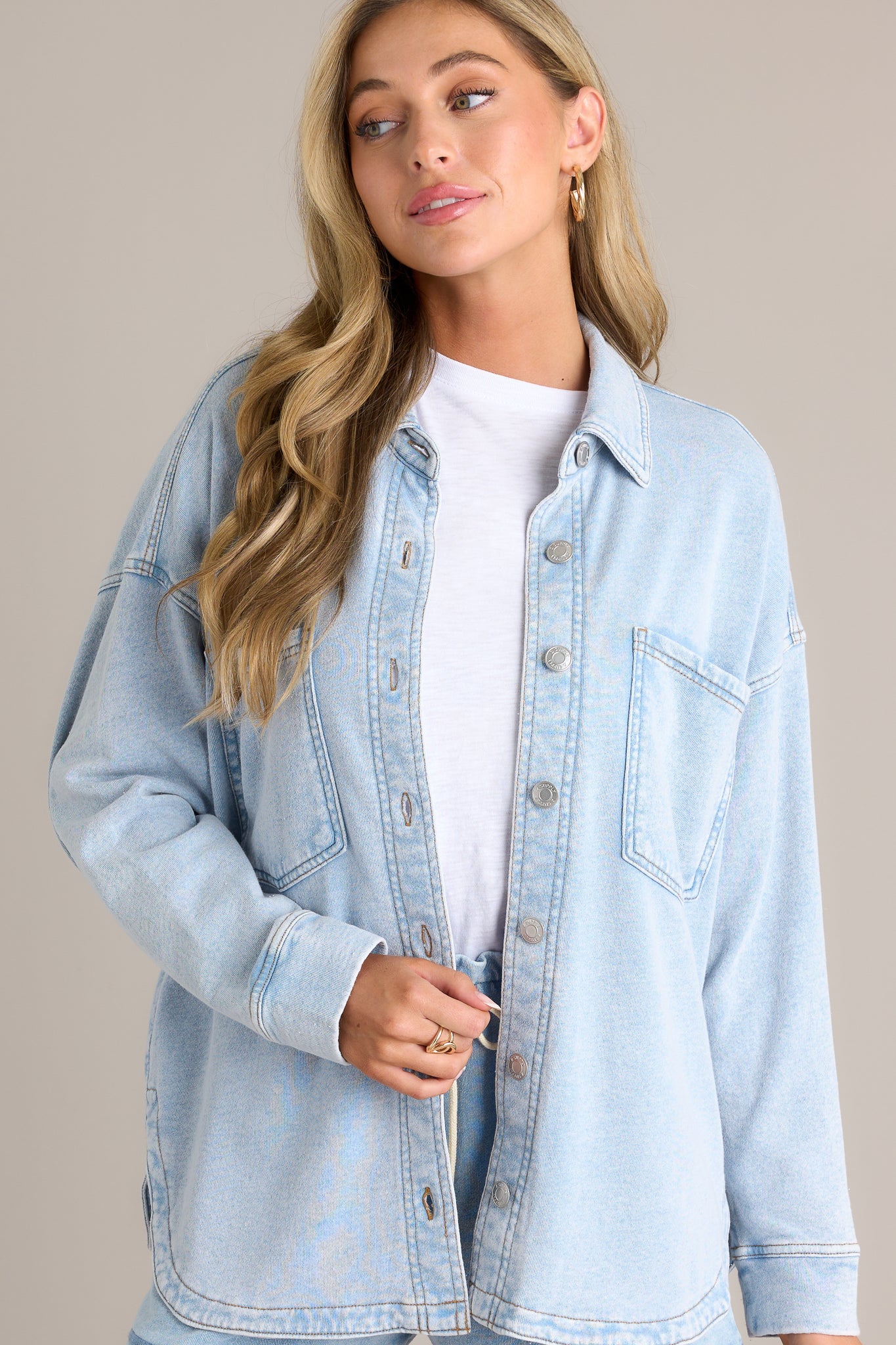 Front angled view of a denim jacket featuring an oversized fit, a functional button front, a curved hemline, and two functional breast pockets