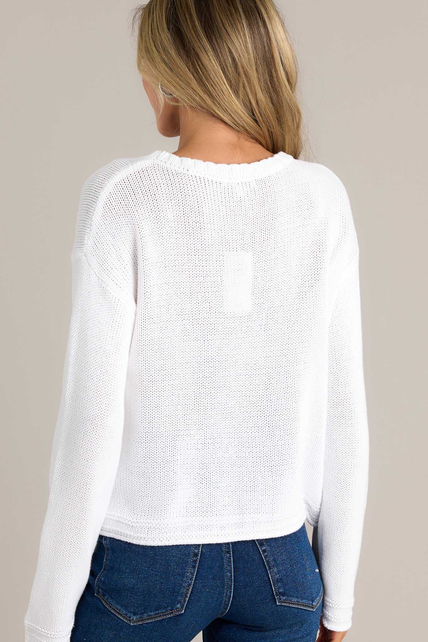 Back view of a sweater highlighting the overall fit, cropped length, and contrast detailing at the hem.