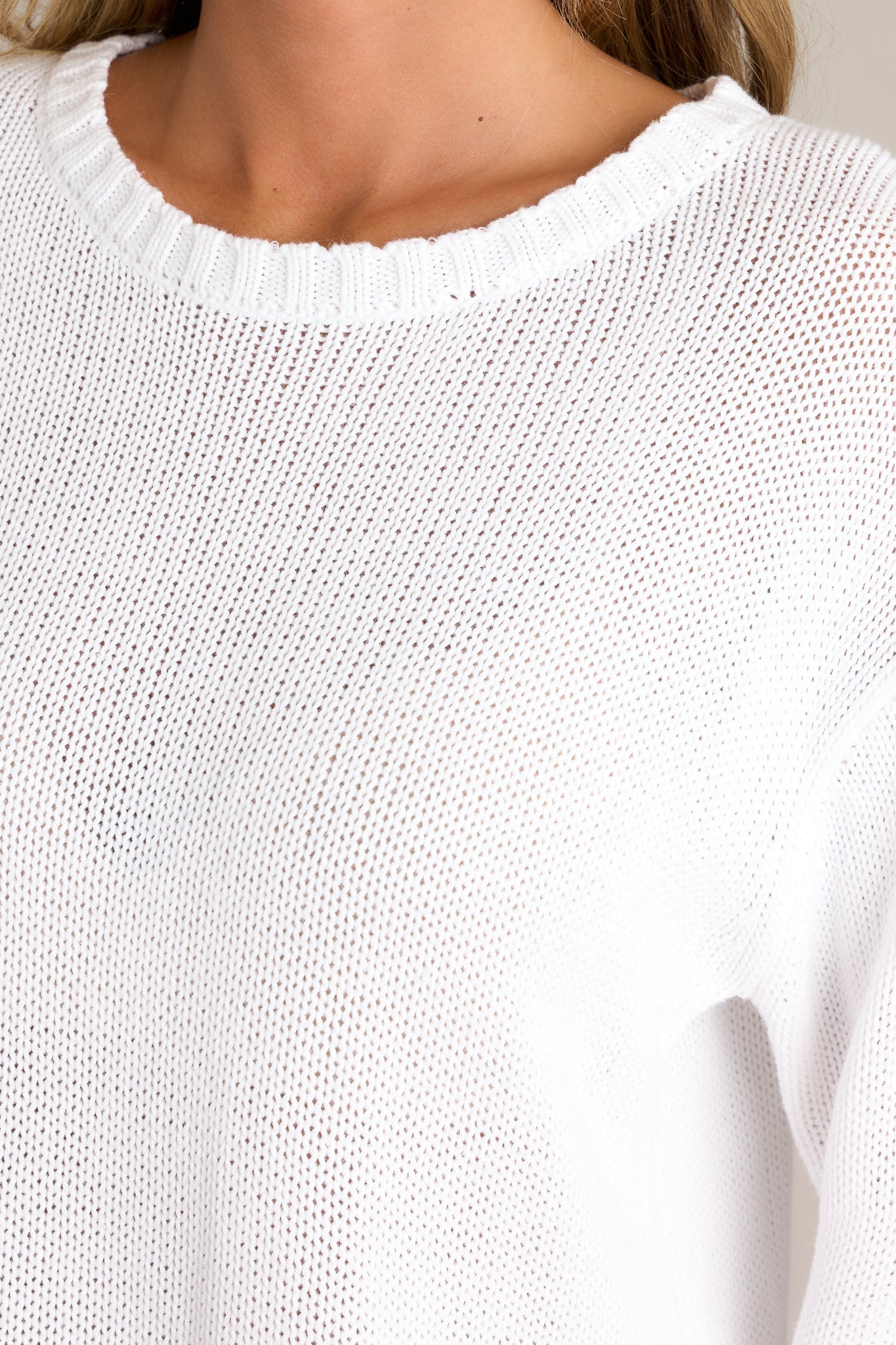 Close-up of the sweater showing the crew neckline, contrast detailing at the hem, and knit detailing around the neckline.