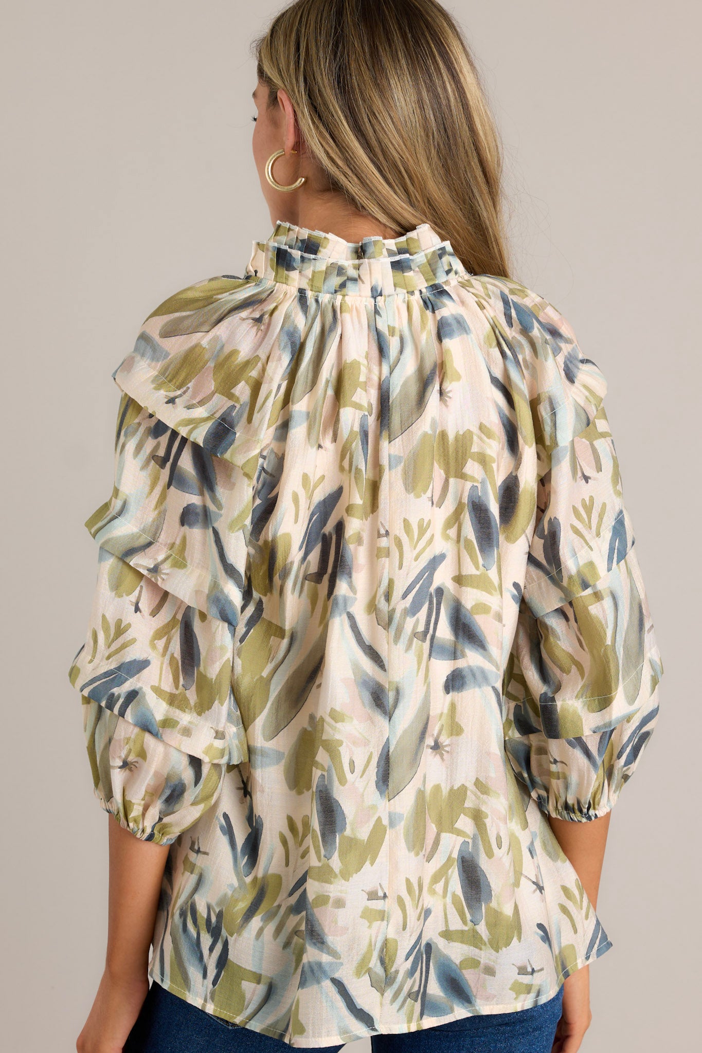 Back view of a beige top highlighting the overall fit, unique print, and elastic cuffed subtly pleated sleeves.