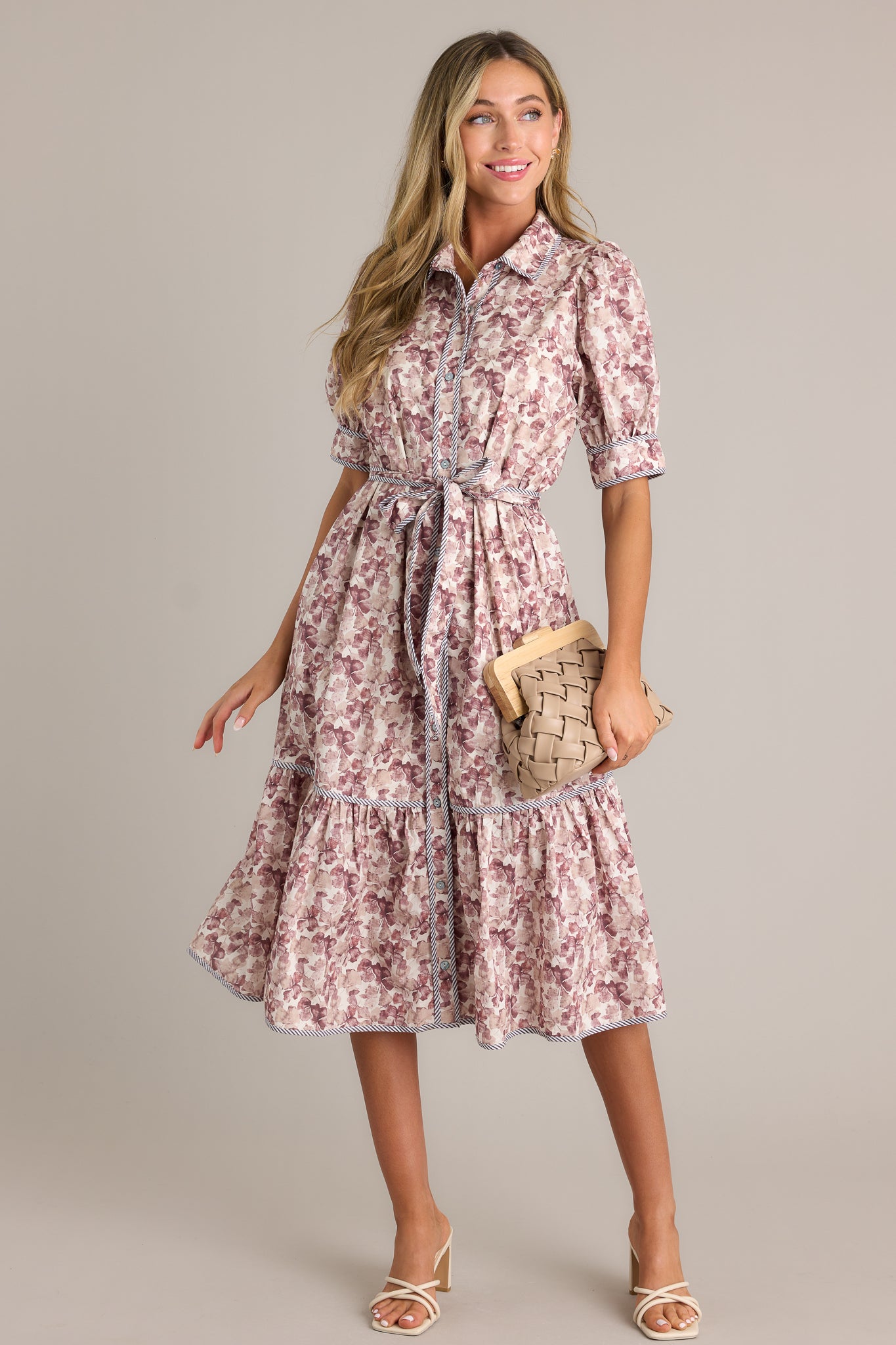 This floral midi dress features a collared neckline, a functional button front, functional hip pockets, a self tie belt on the waist, a tiered design and puff sleeves.