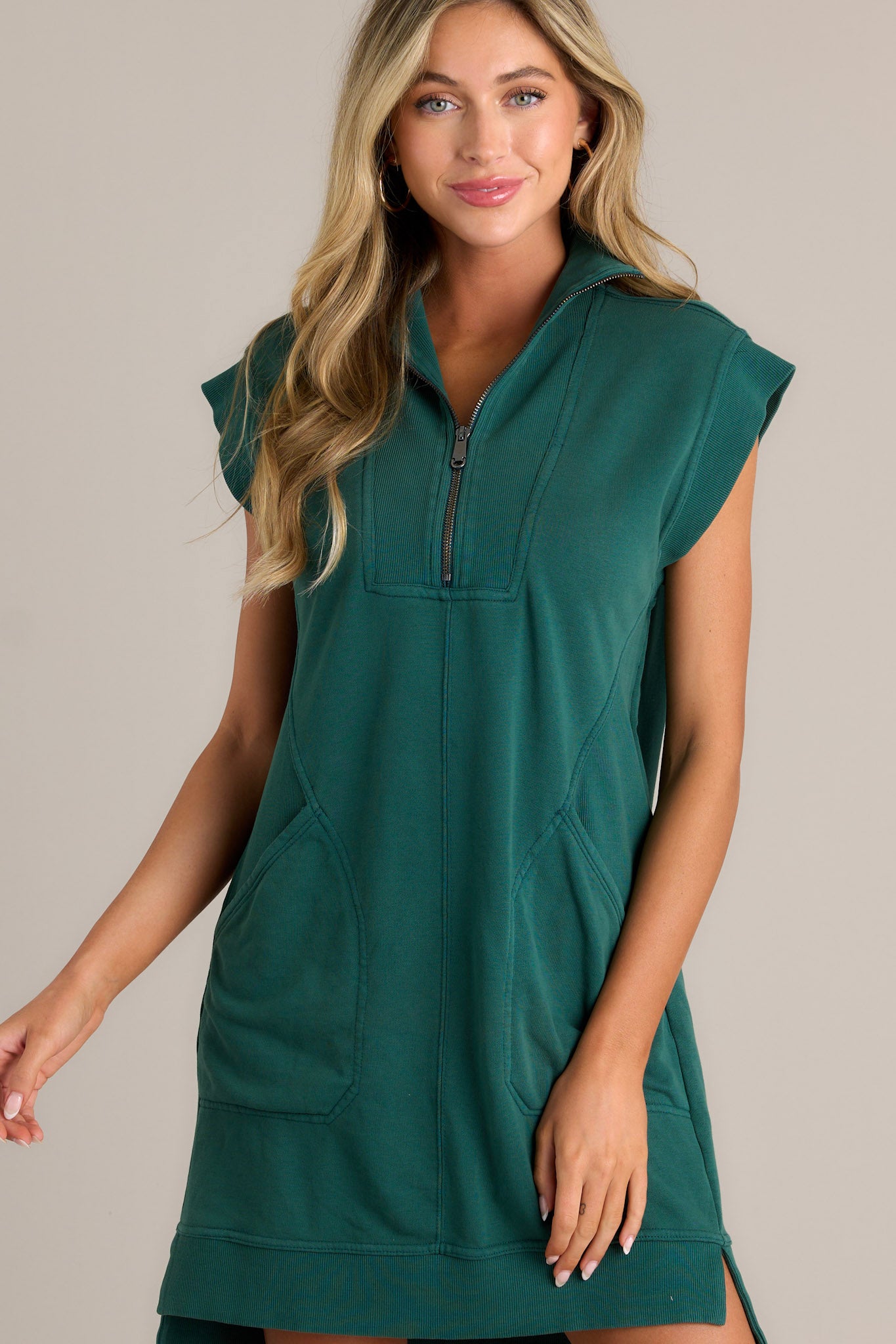 Front view of a hunter green mini dress featuring a collared v-neckline, a functional zipper front, ribbed detailing, functional front pockets, a split hemline, and wide ribbed sleeves.