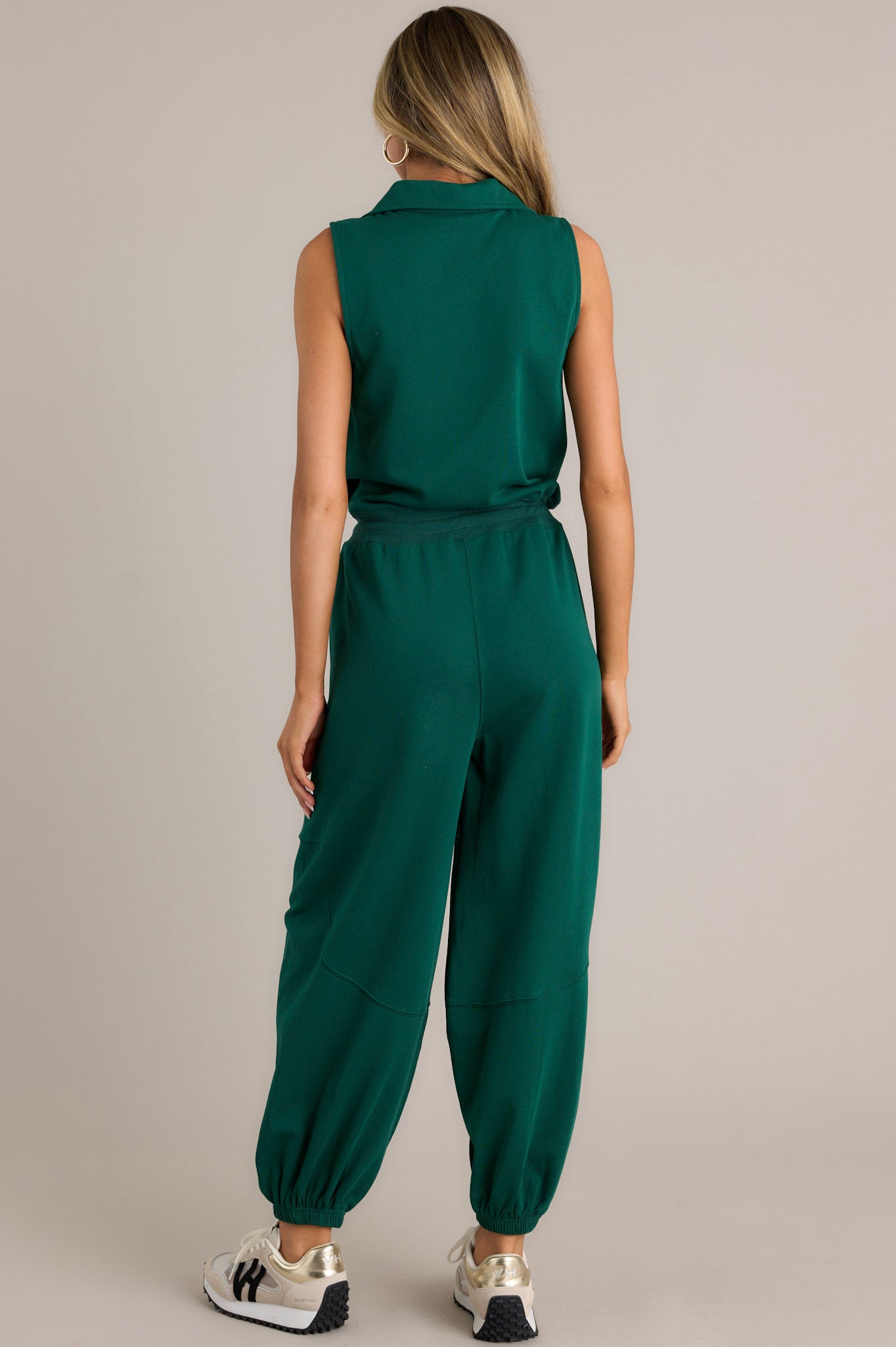 Back view of a green jumpsuit highlighting the overall fit, collared neckline, and elastic cuffed ankles.