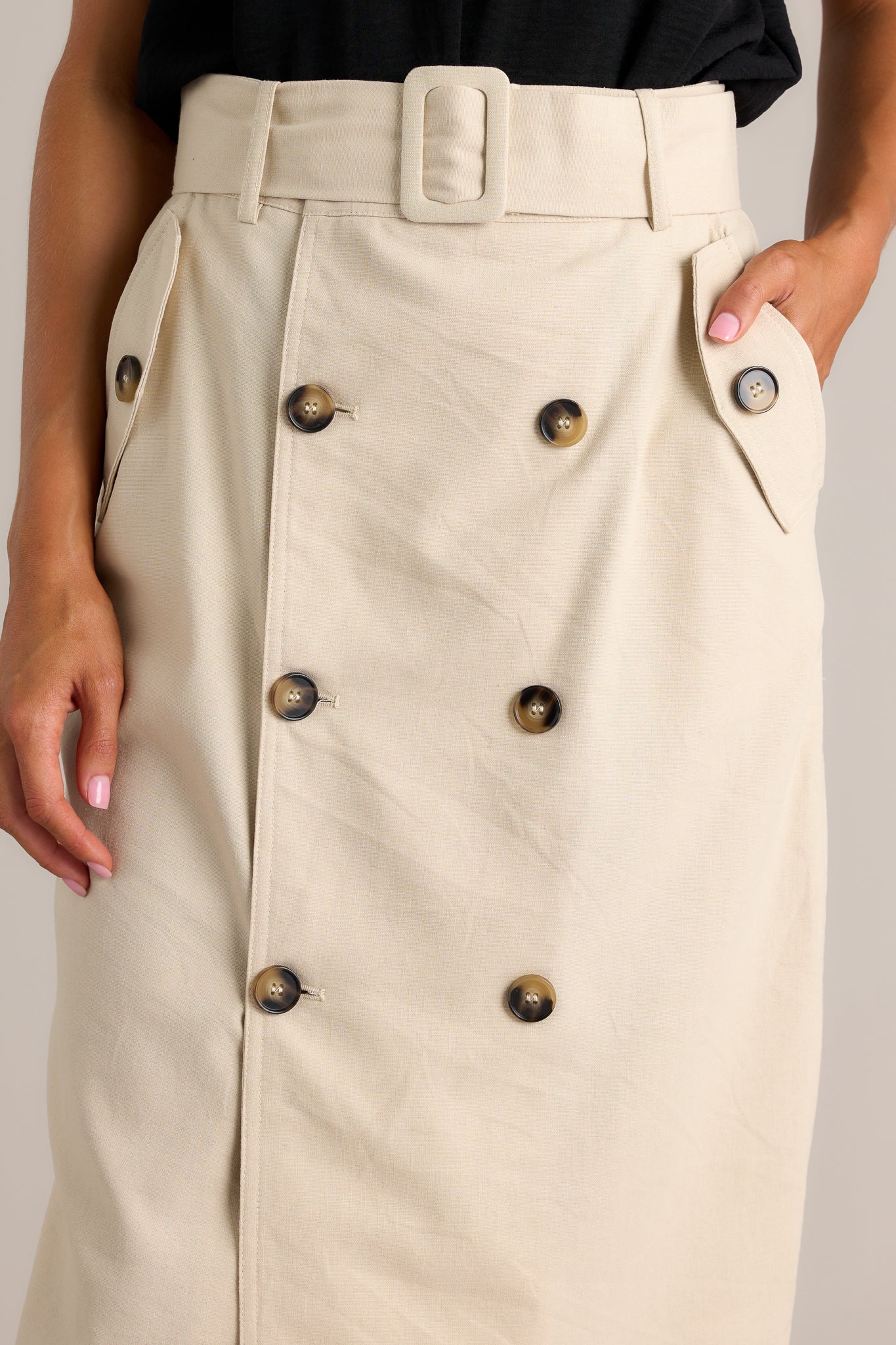 Detail shot of the buttons and belt on this light beige maxi skirt. 