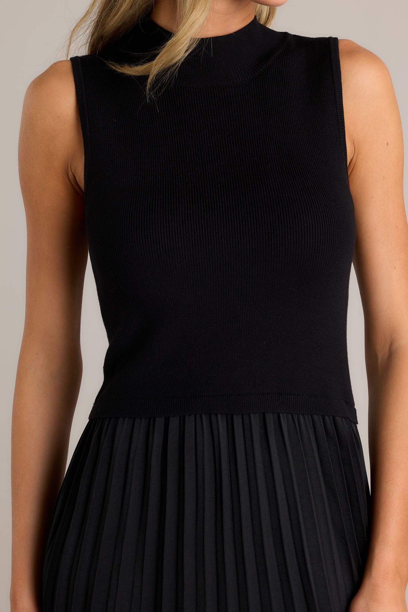 Close up of the sleeveless, ribbed bodice and high neck on this black maxi dress.