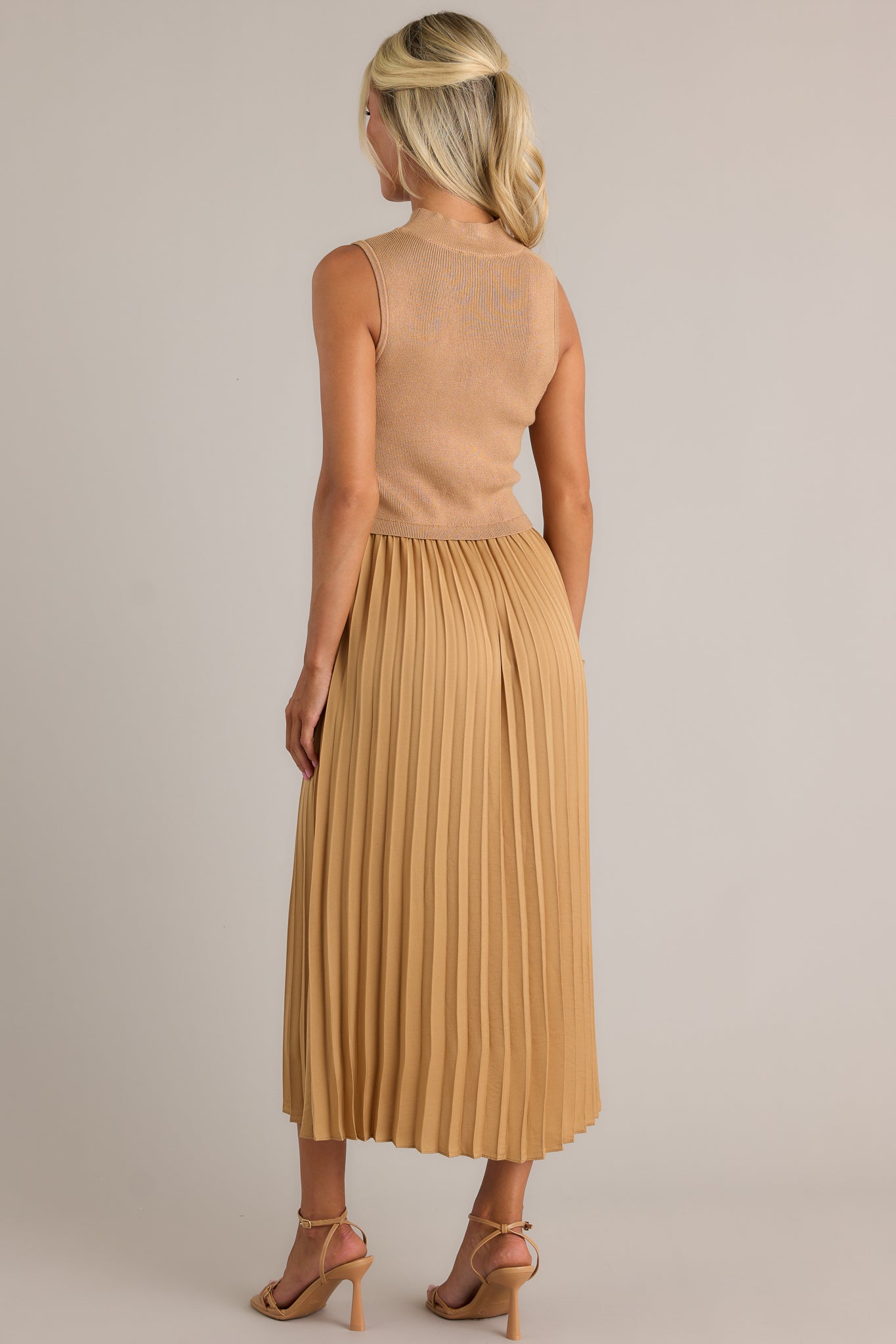 Back view of this mustard sleeveless dress featuring a high neckline, a ribbed knit bodice, a pleated skirt, a sleeveless design and a flowing silhouette.