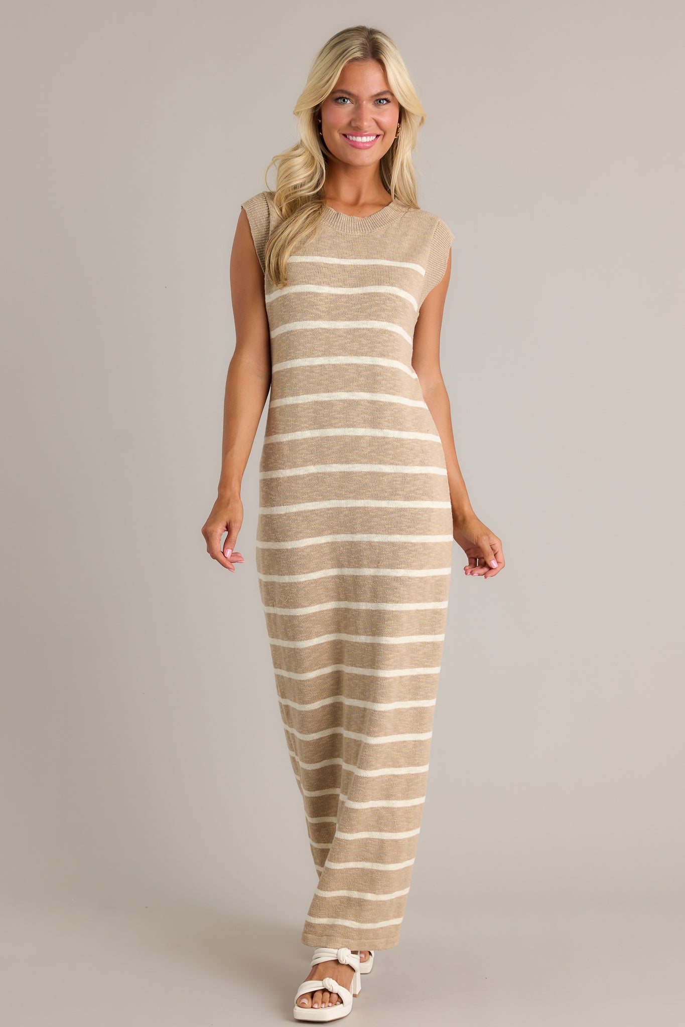 Full length view of a taupe dress with a ribbed neckline, a small leg slit, and a lightweight knit fabric