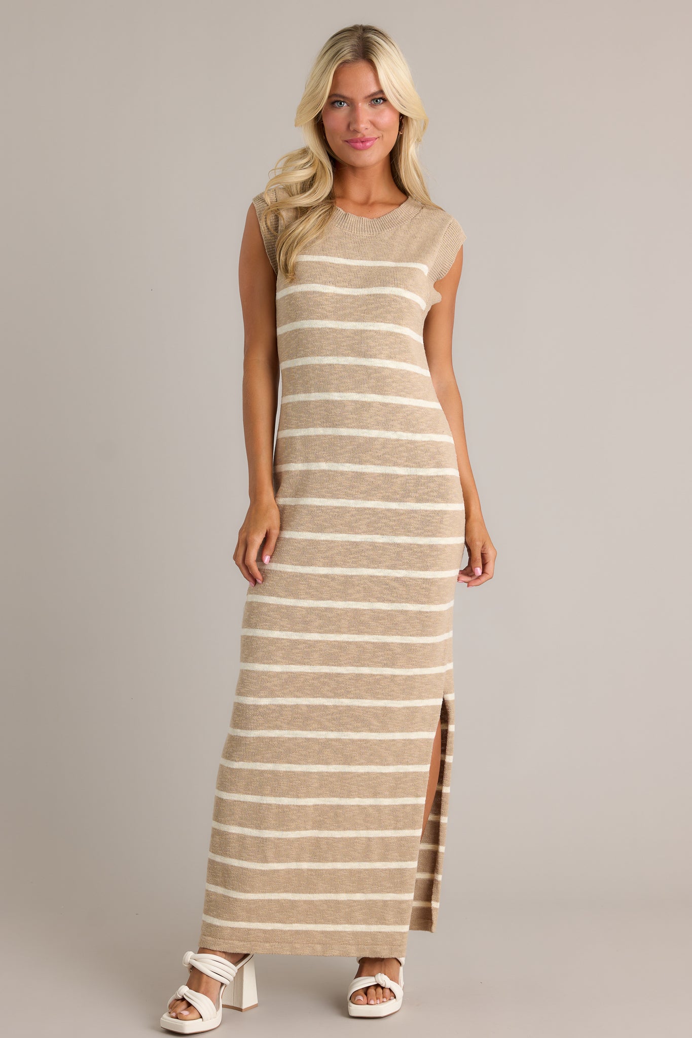 Front angled view of a taupe dress featuring a ribbed neckline, a small leg slit, and a lightweight knit fabric