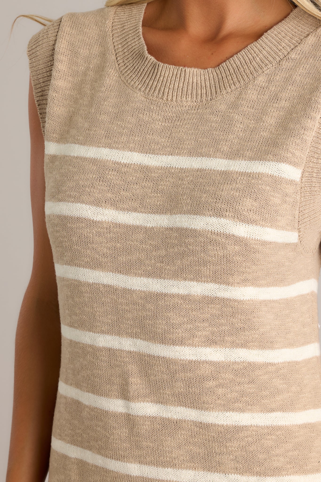 Close-up of the taupe dress showing the ribbed neckline and the texture of the lightweight knit fabric.