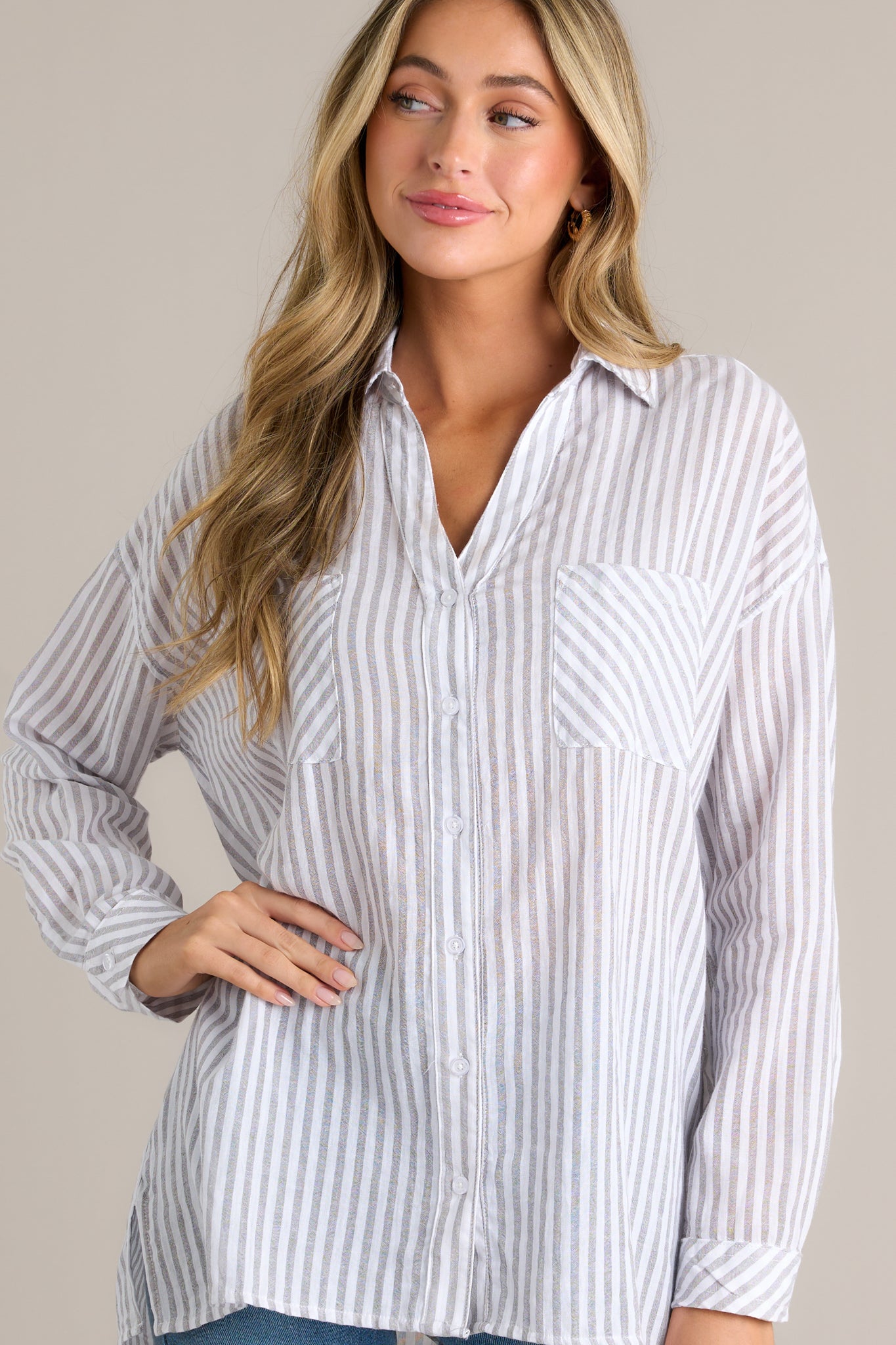 This top features a collared neckline, buttons down the front, two pockets at the bust, buttoned cuffs, and a lightweight material.