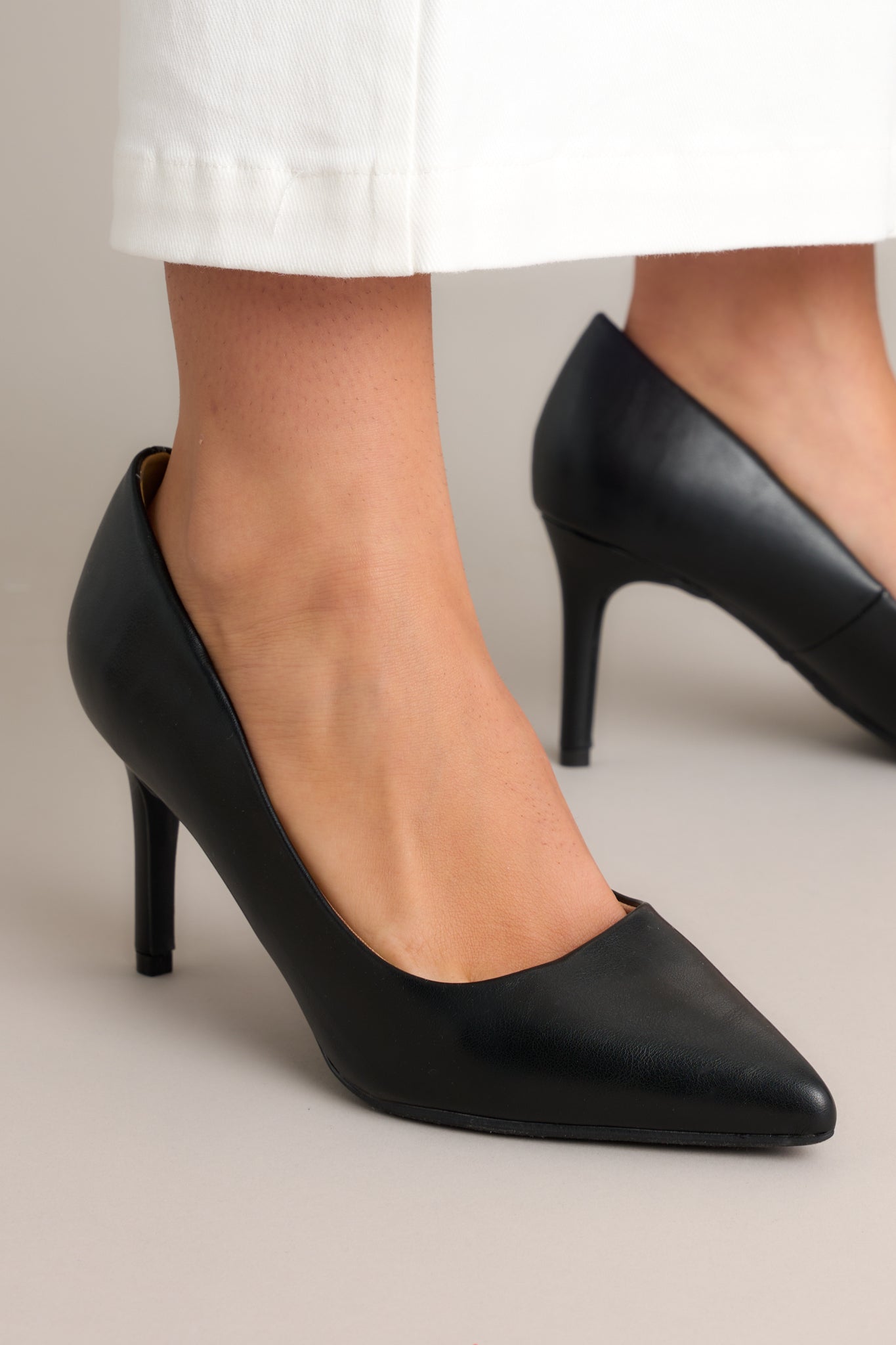 Close-up view of these black pump heels features a pointed toe and extra cushioning in the middle of the shoe.