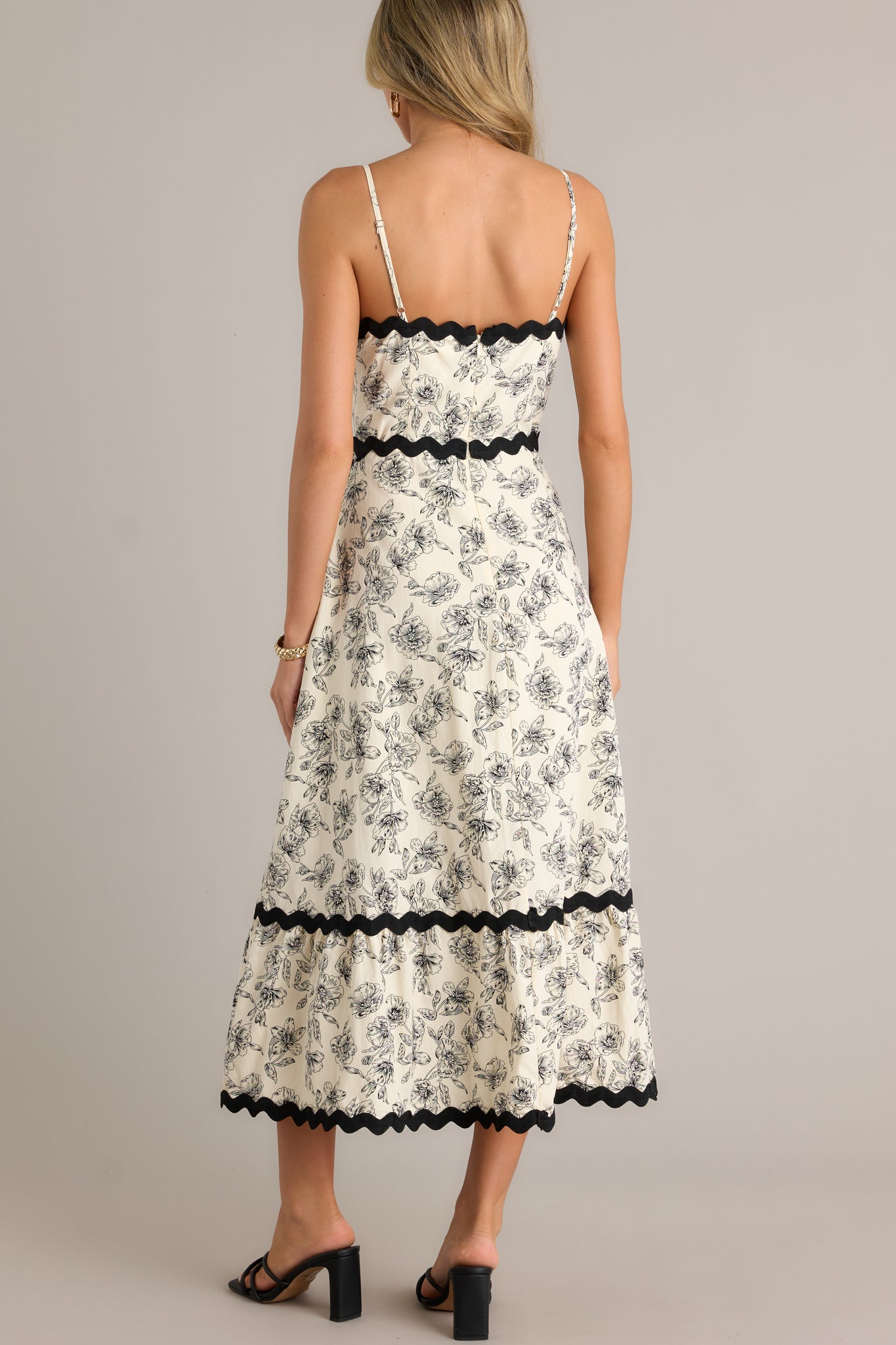 Back view of the ivory maxi dress highlighting the discrete back zipper, the tiered design, and the black ruffle trim on the straps.