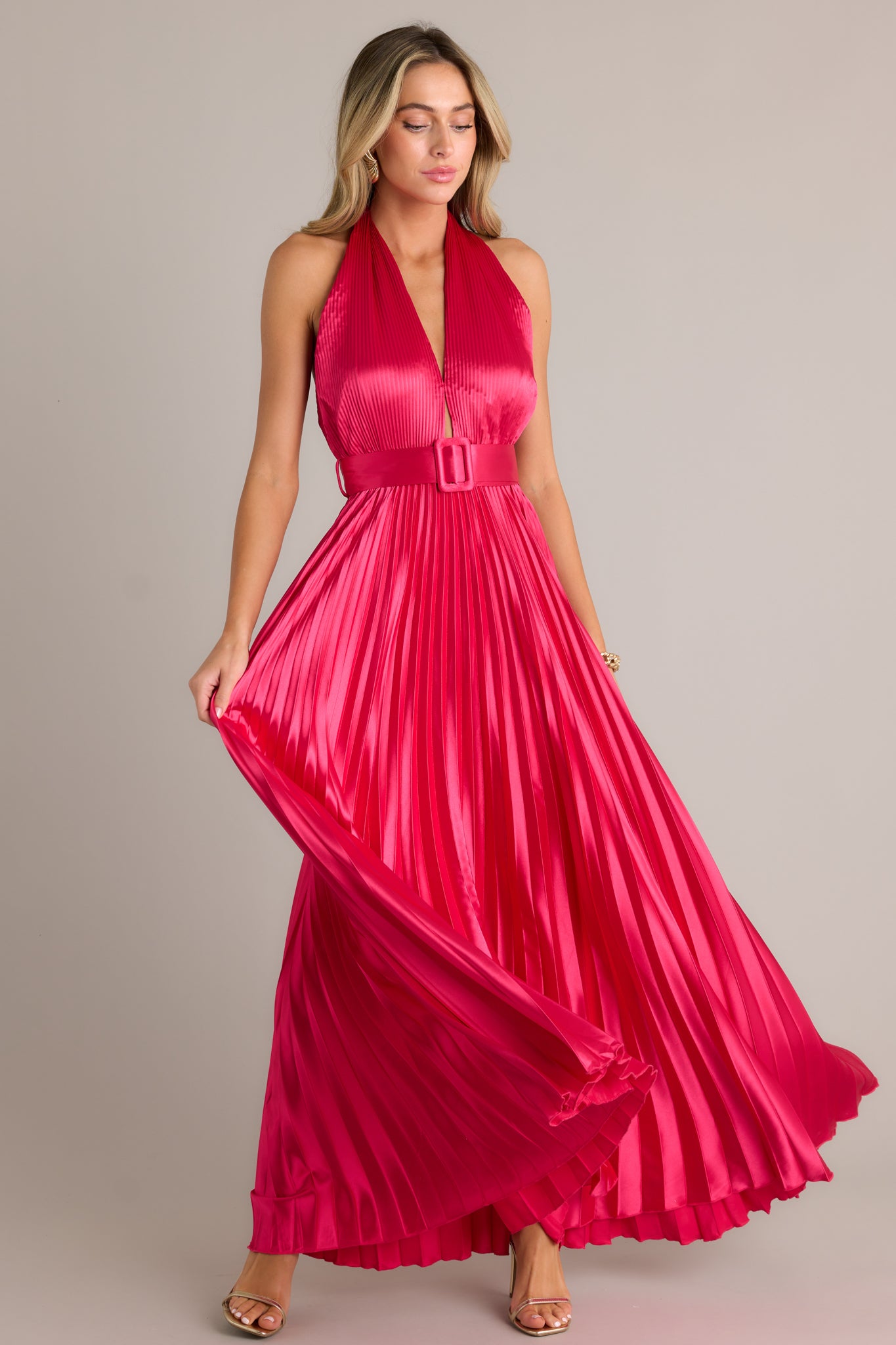 The vibrant pink color and beautiful pleats will make you stand out in any crowd. This magenta pink dress features a functional belt, a halter neck tie, and a functional zipper on the back.