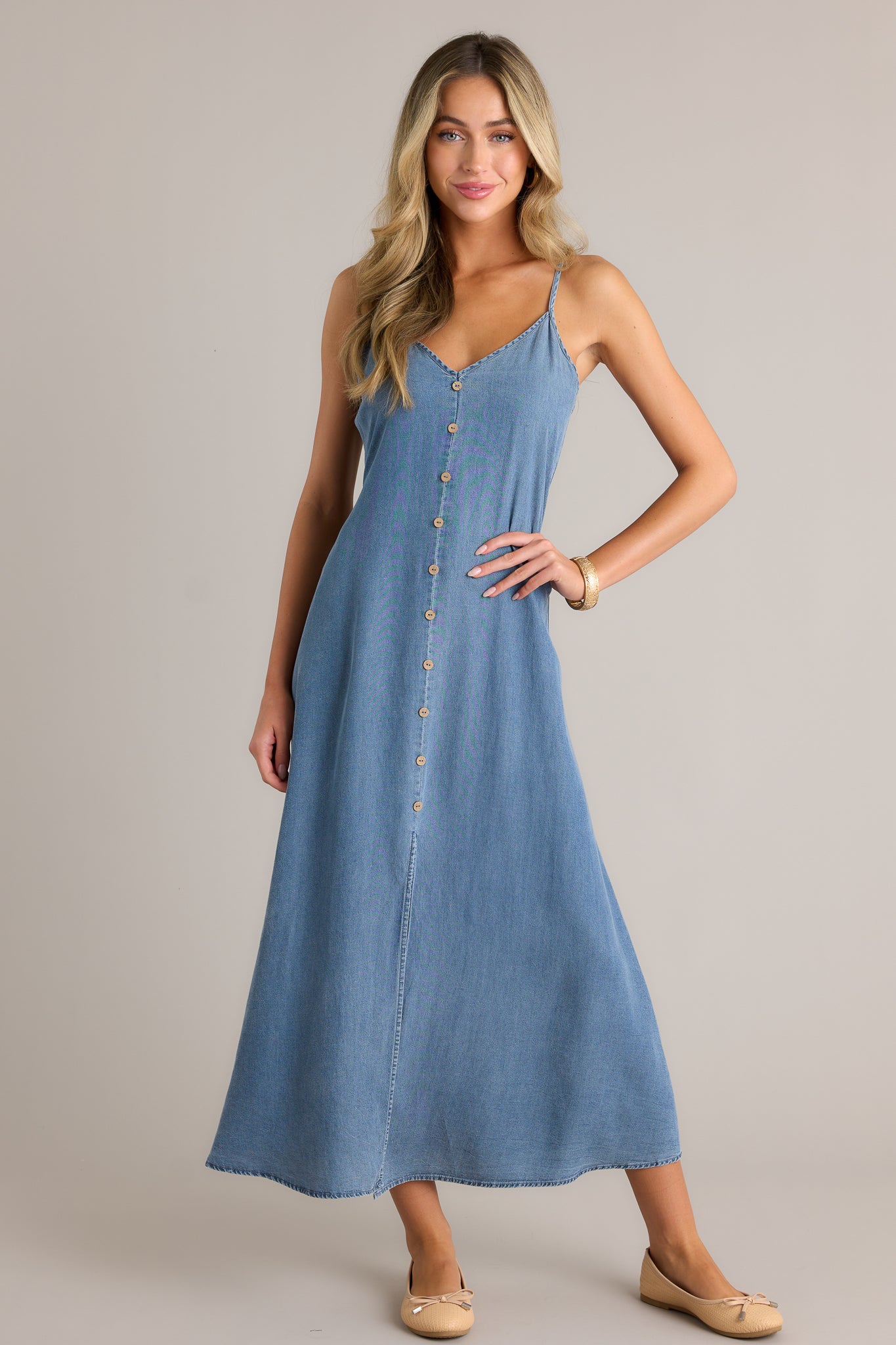 This chambray maxi dress features a v-neckline, a button front design, a smocked back insert, adjustable spaghetti straps and an open leg slit.