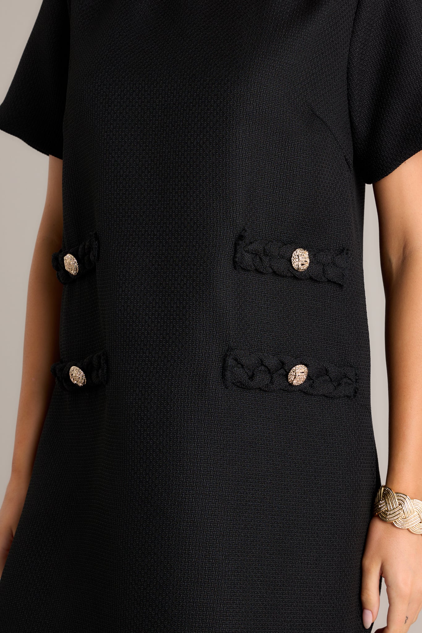 Detailed view of the gold button detailing on the faux braided pockets.