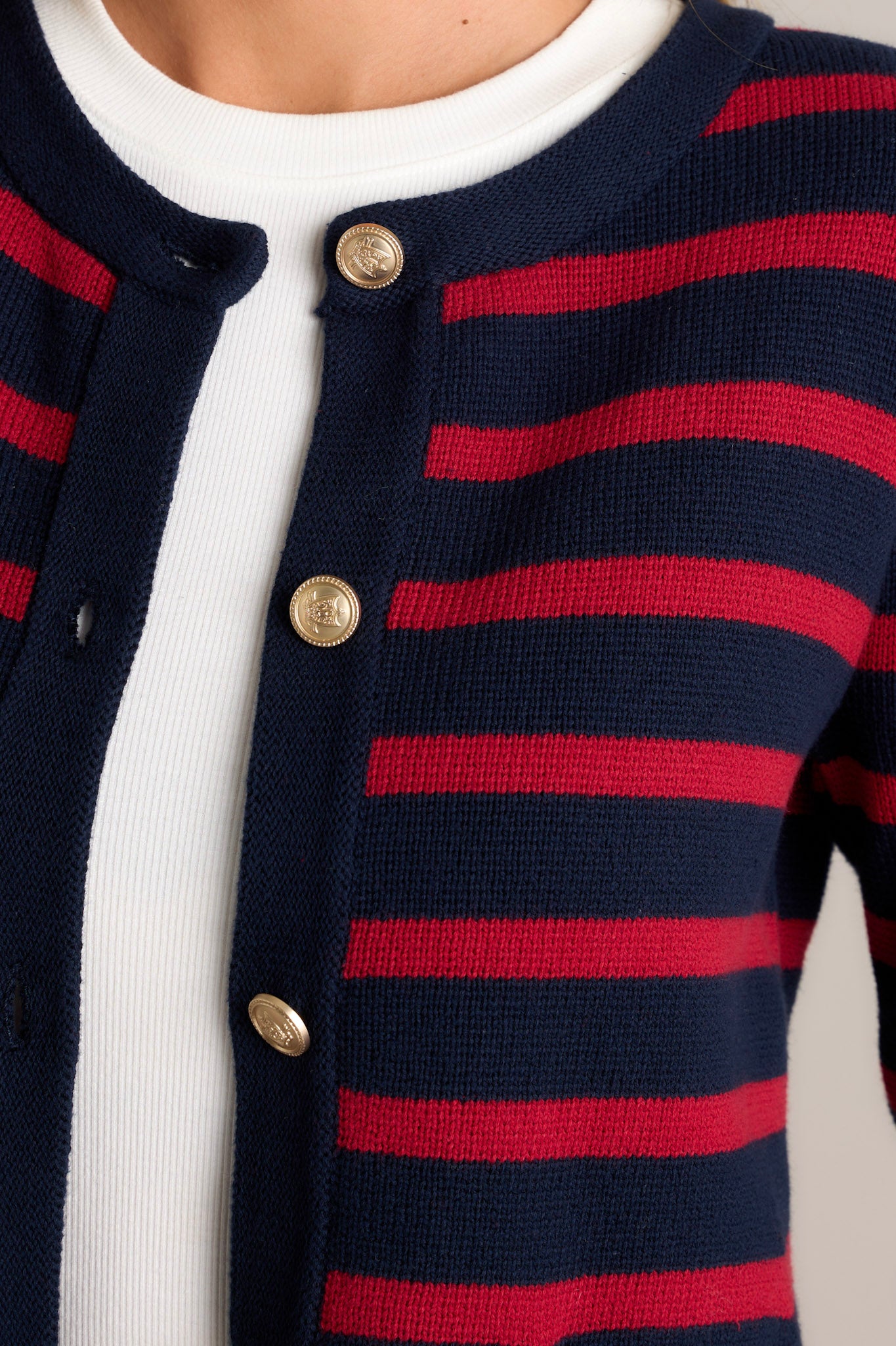 Close-up of the cardigan showing the detailed gold buttons, crew neckline, and the texture of the fabric.