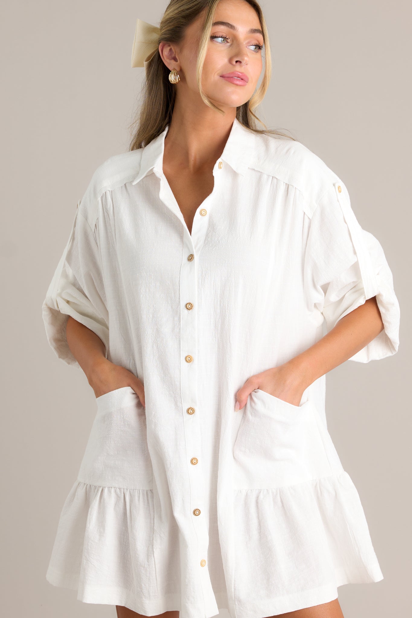 Front view of a button front dress featuring a collared high neckline, a functional button front, functional hip pockets, cuffed half sleeves, and a tiered design.