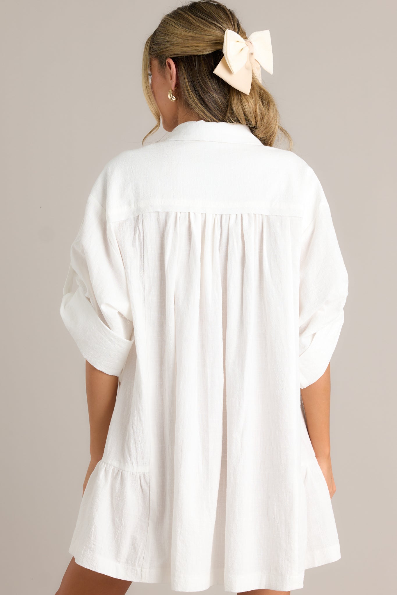 Back view of a button front dress highlighting the overall fit, cuffed half sleeves, and the tiered design.