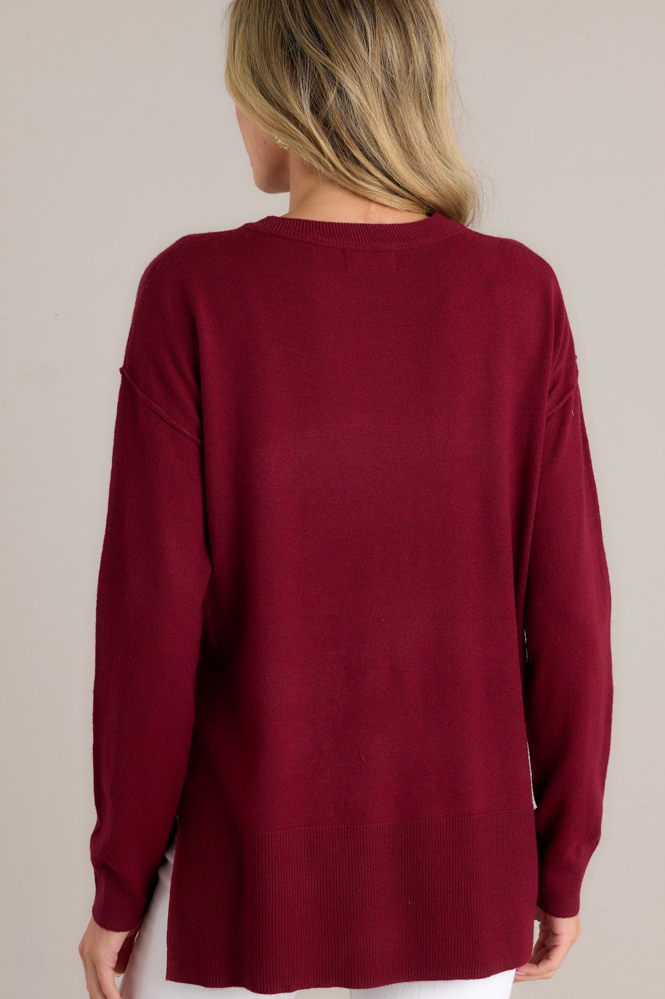 Back view of this sweater that features a round neckline, long sleeves with ribbed cuffs, a bottom hemline that is slightly longer in the back and has slits up both sides, and a super soft feel throughout.