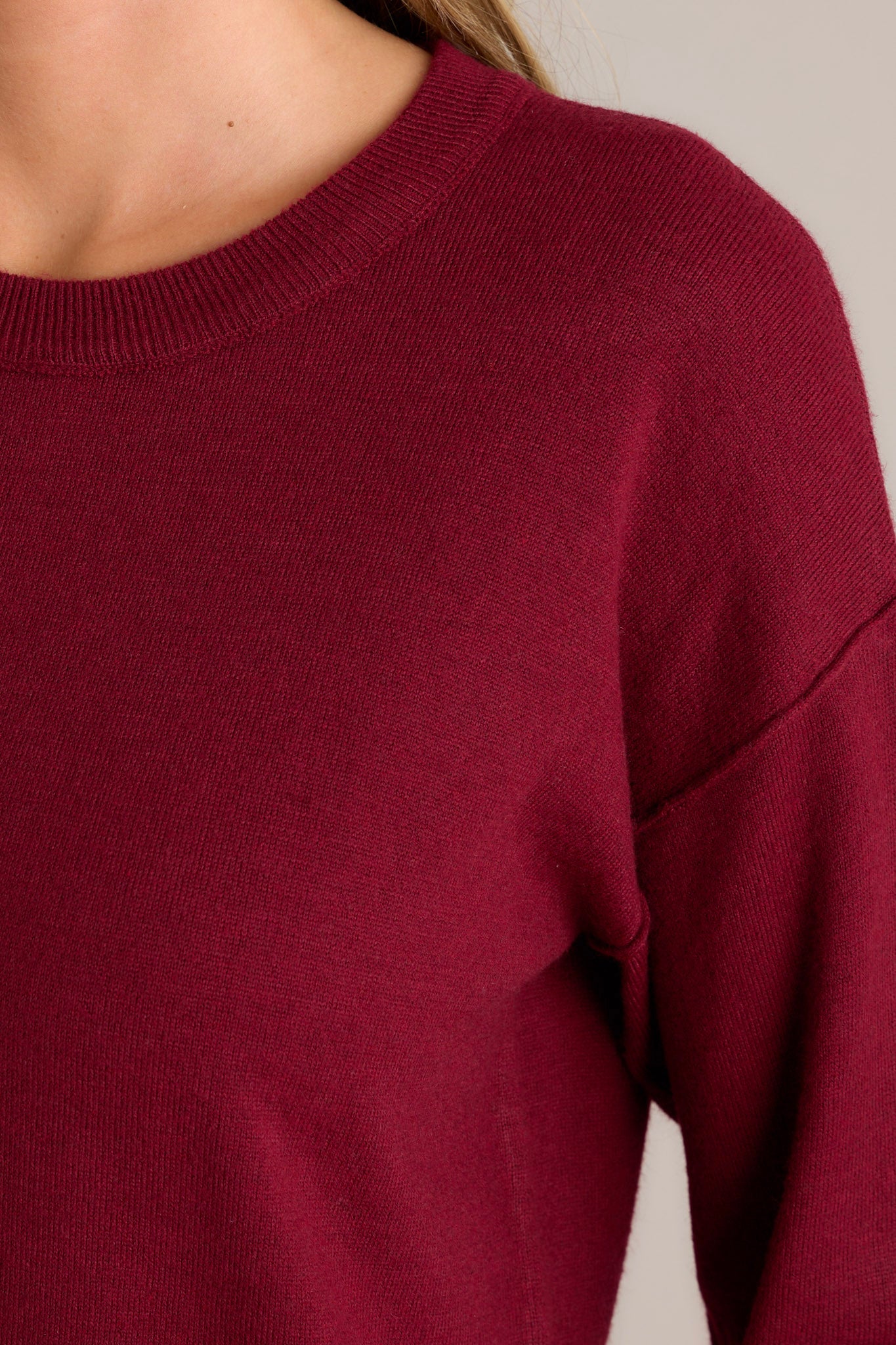 Close-up view of this sweater that features a round neckline, long sleeves with ribbed cuffs, a bottom hemline that is slightly longer in the back and has slits up both sides, and a super soft feel throughout.