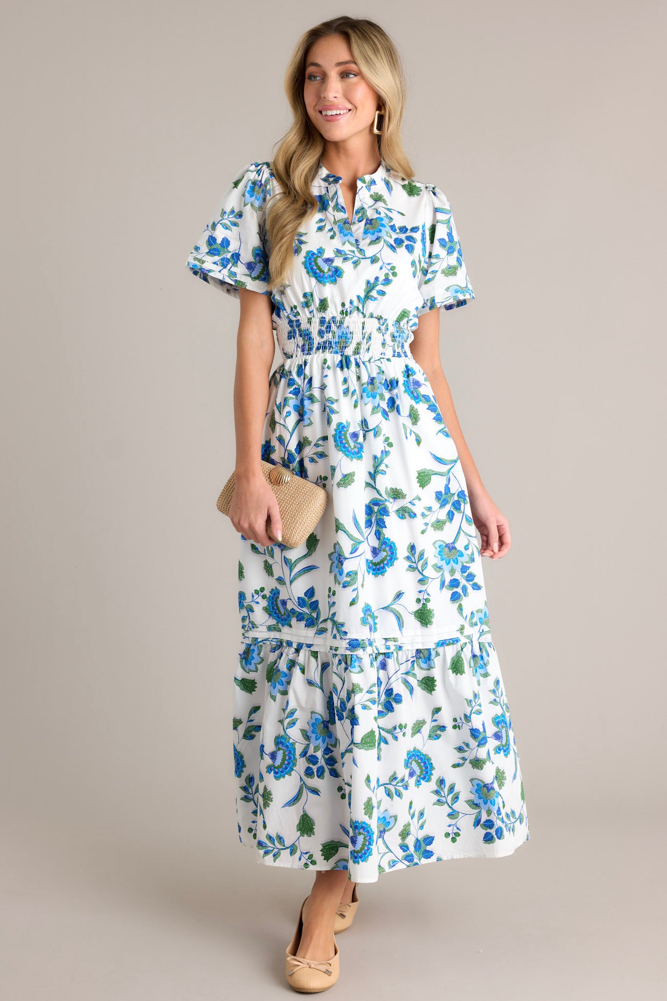 Full length view of a blue floral dress featuring a stretchy waistband, a small V-neck, and blue appliqué florals