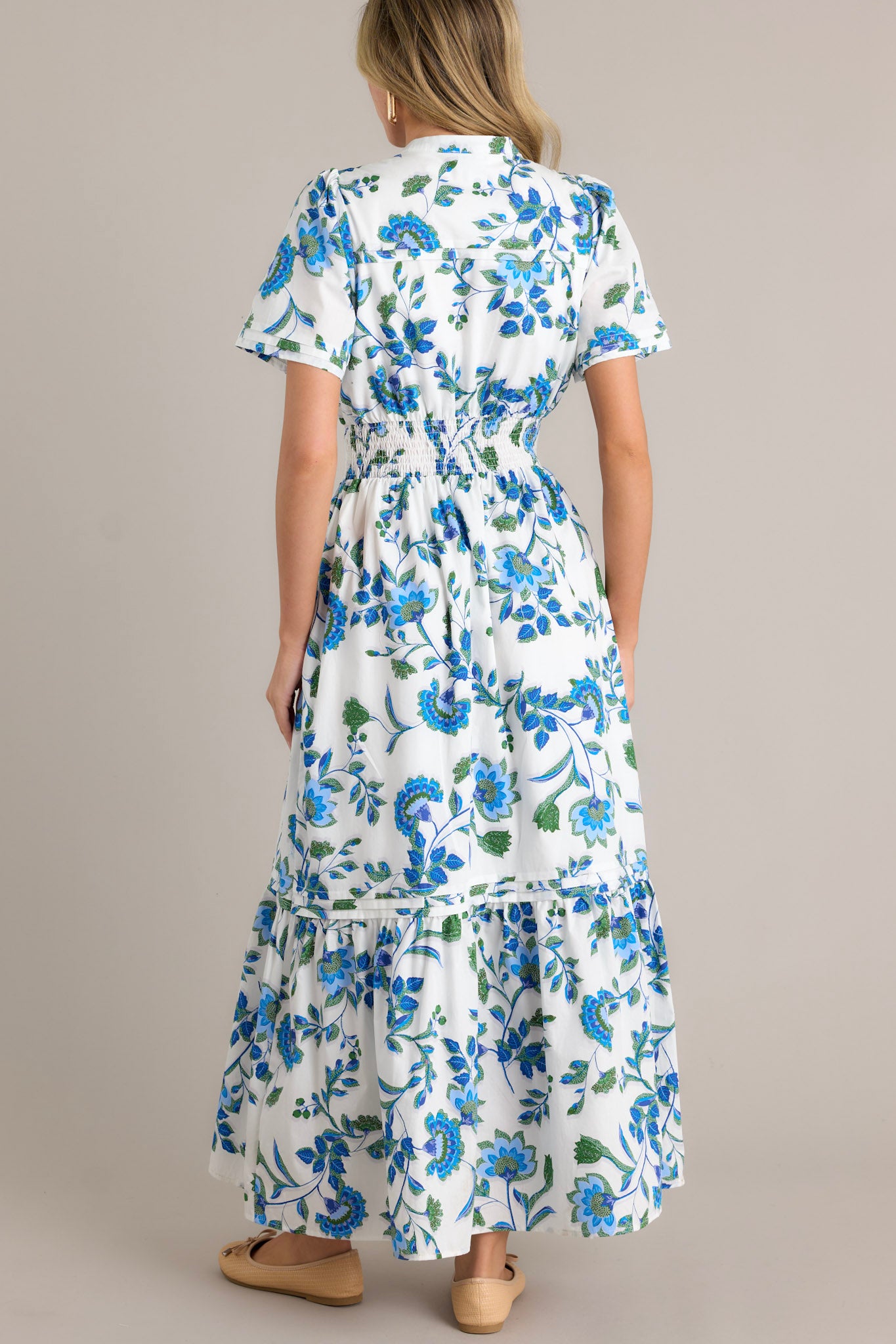 Back view of a blue floral dress highlighting the flow of the fabric and the placement of the blue appliqué florals.