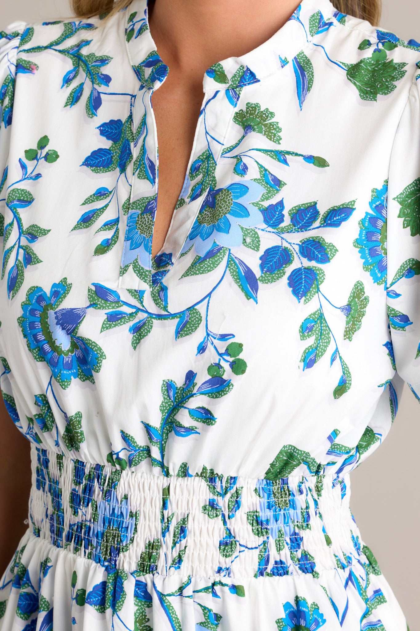 Close-up of a blue floral dress showing the small V-neck, the stretchy waistband, and the intricate blue appliqué florals.