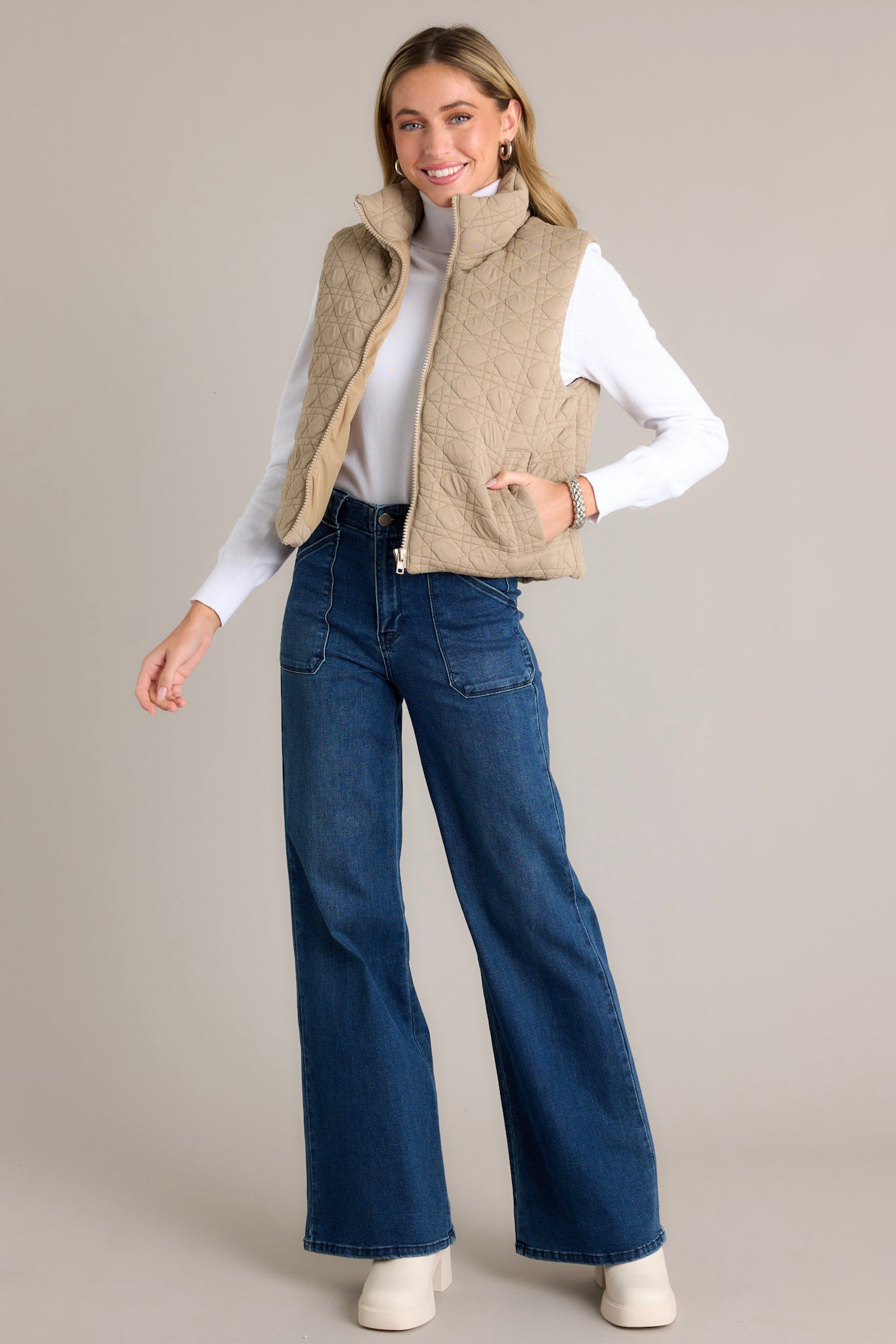 A tan vest with a quilted design, collared neckline, full zip closure, and functional pockets, shown from the front