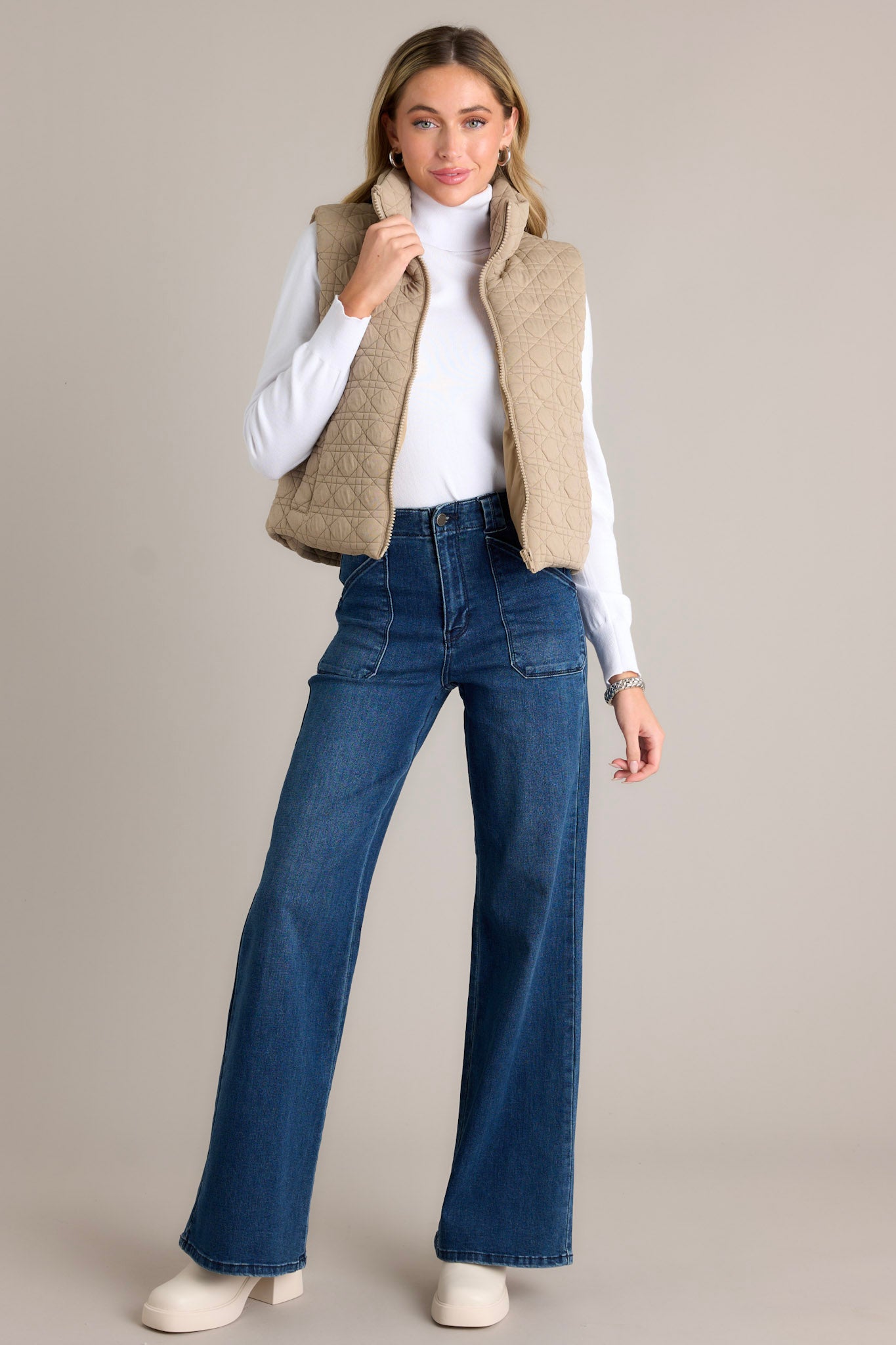 Front view of a tan quilted vest featuring a collared neckline, full zip closure, and functional pockets.