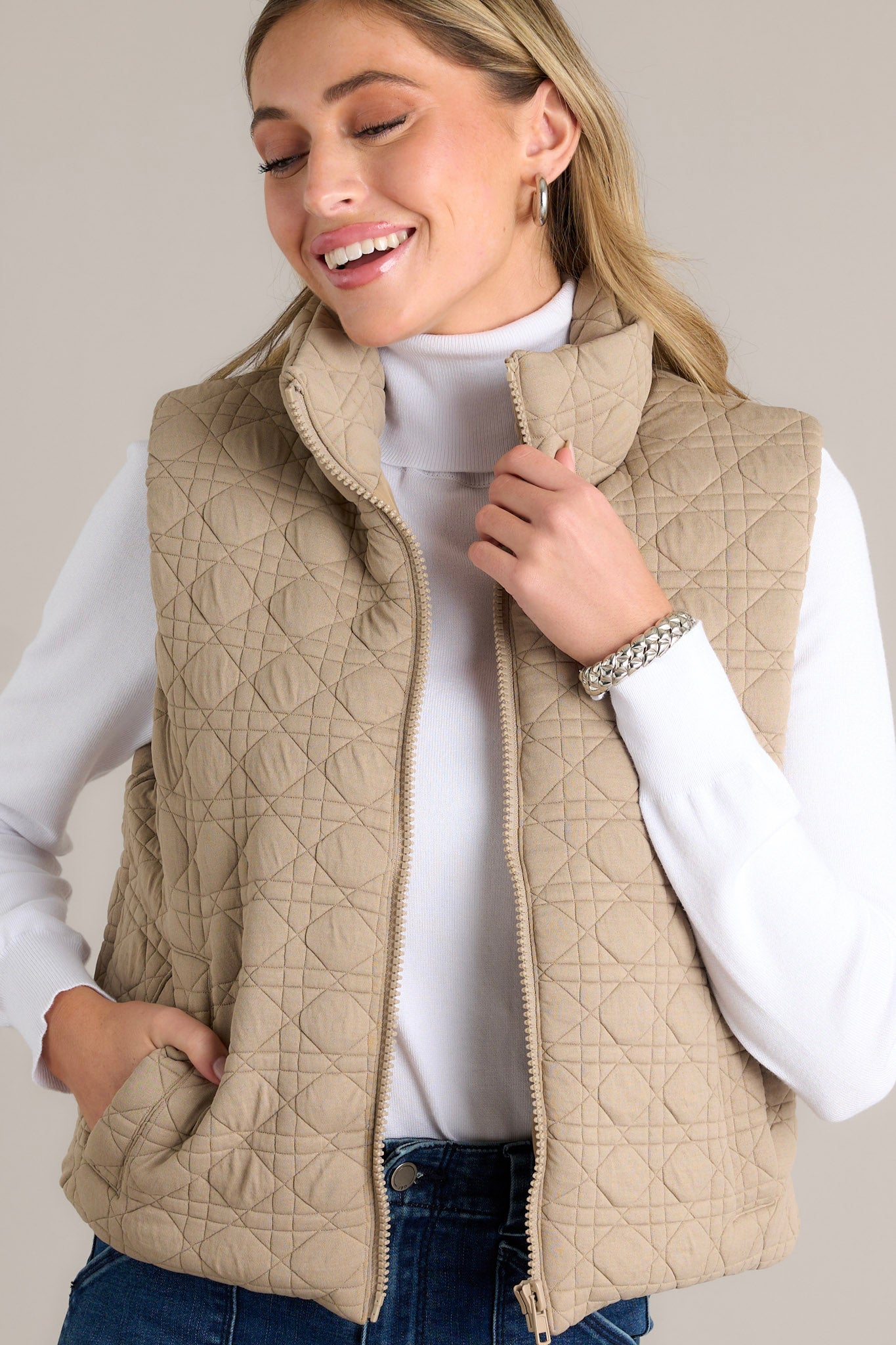 Detailed view of the tan quilted vest highlighting the collared neckline, full zip closure, and functional pocket.