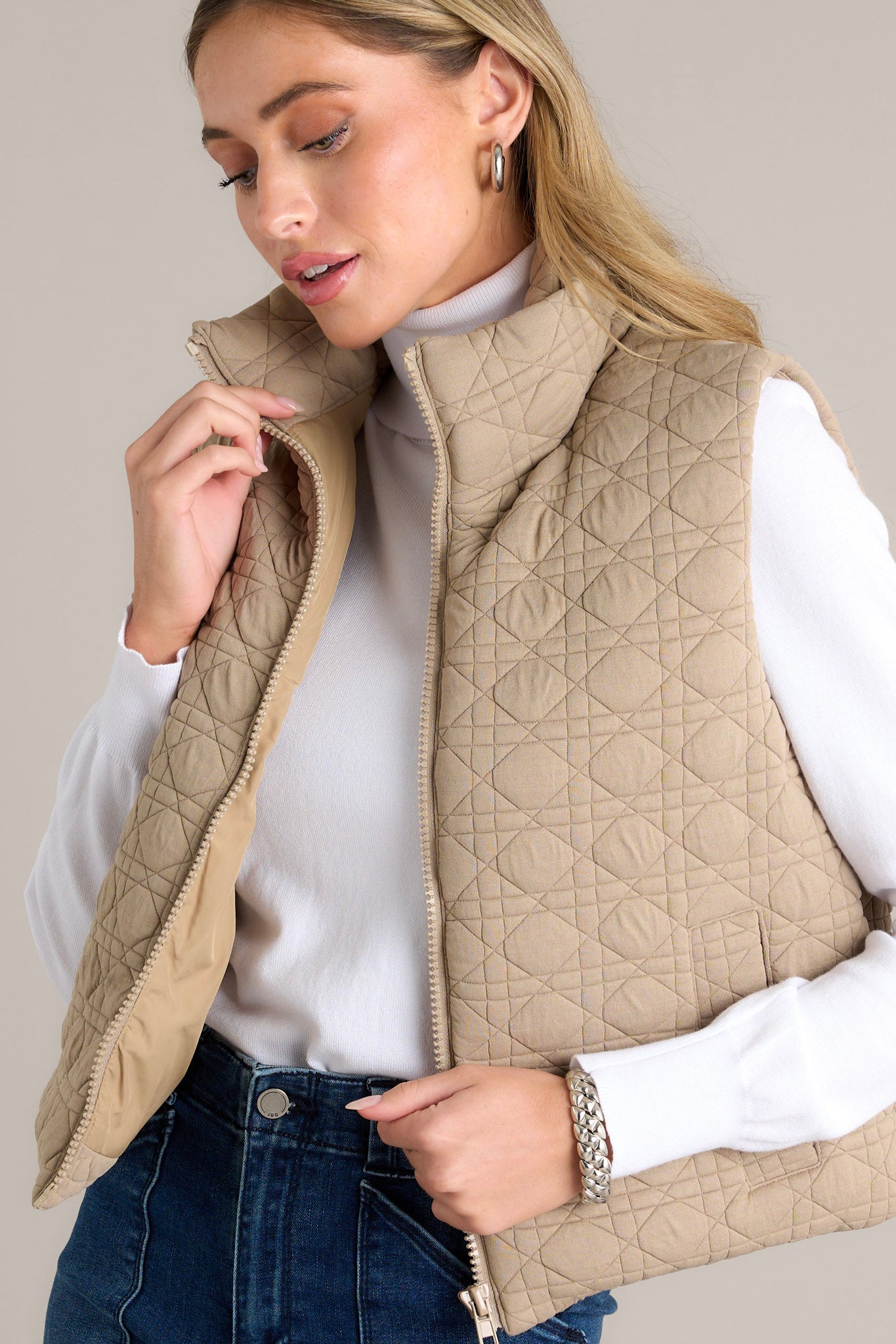 Close-up of a tan vest showcasing its quilted design, collared neckline, and full zip closure.