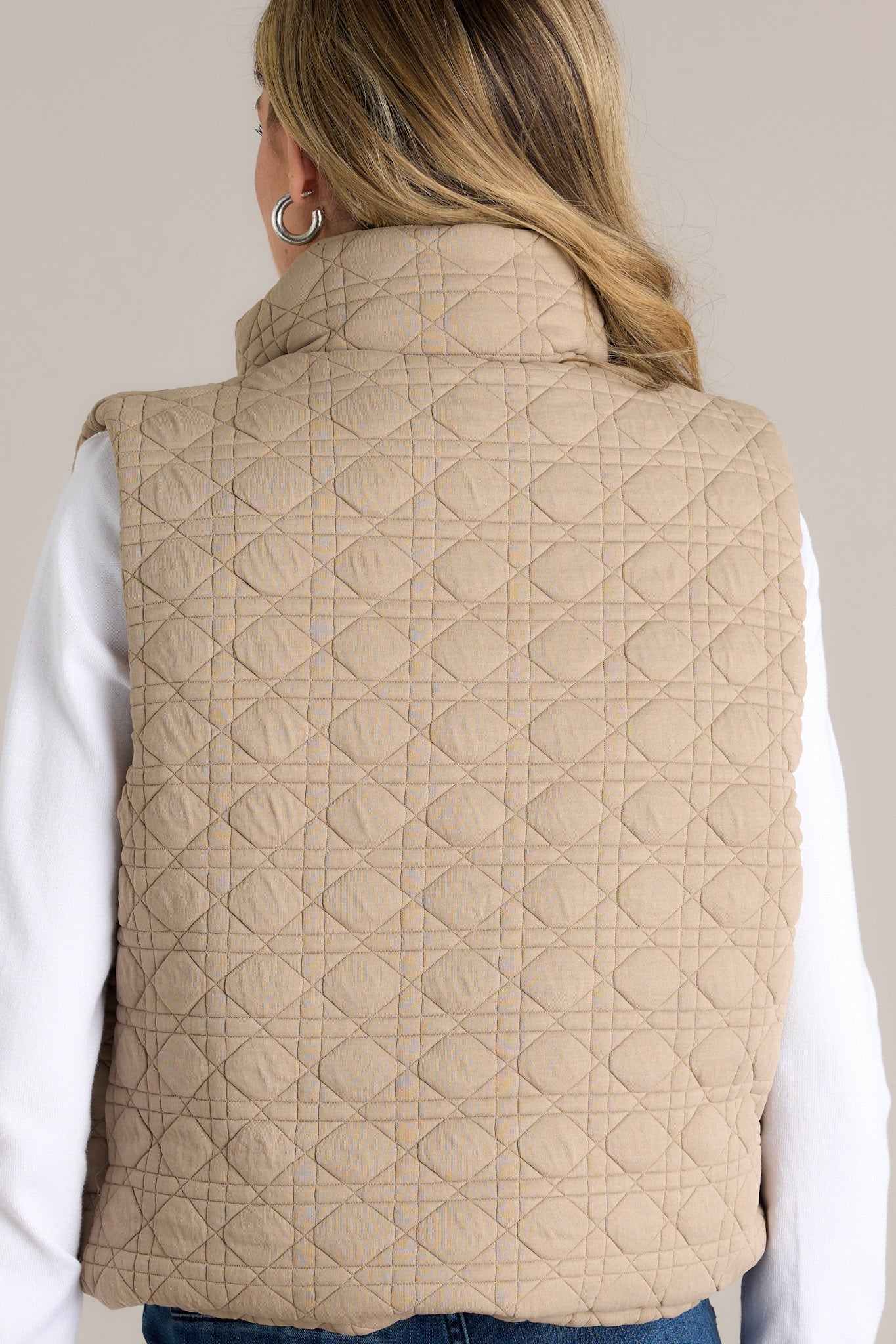 Back view of the tan quilted vest displaying its detailed stitching and collared neckline.