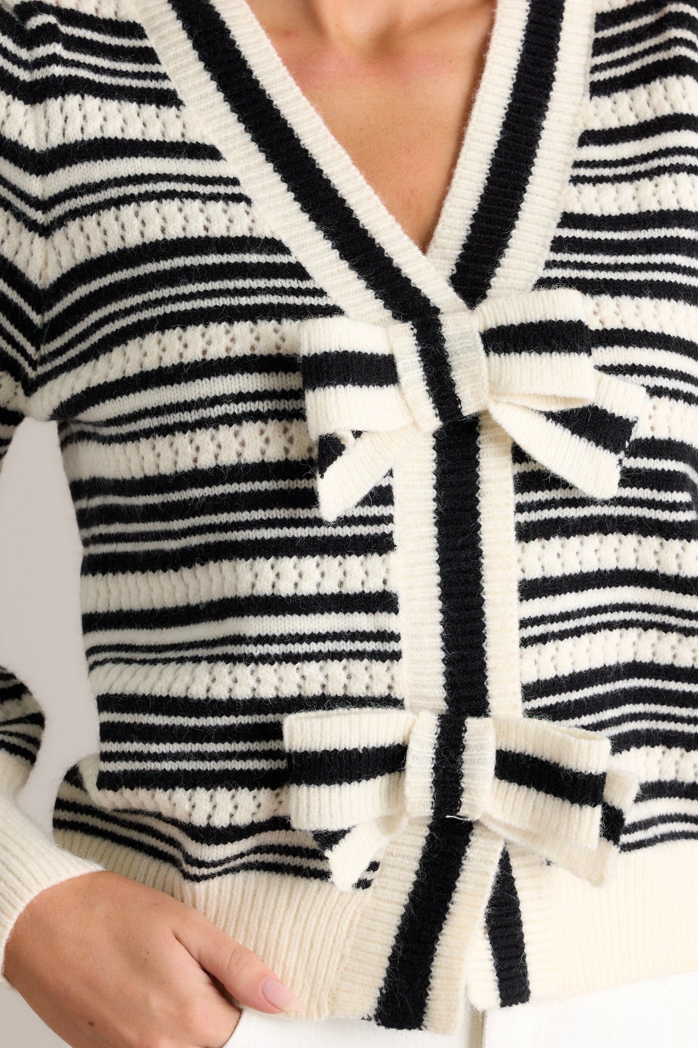 Close-up detail of the stripe sweater top showing the classic horizontal stripe design, v-neckline, and bow tie details.