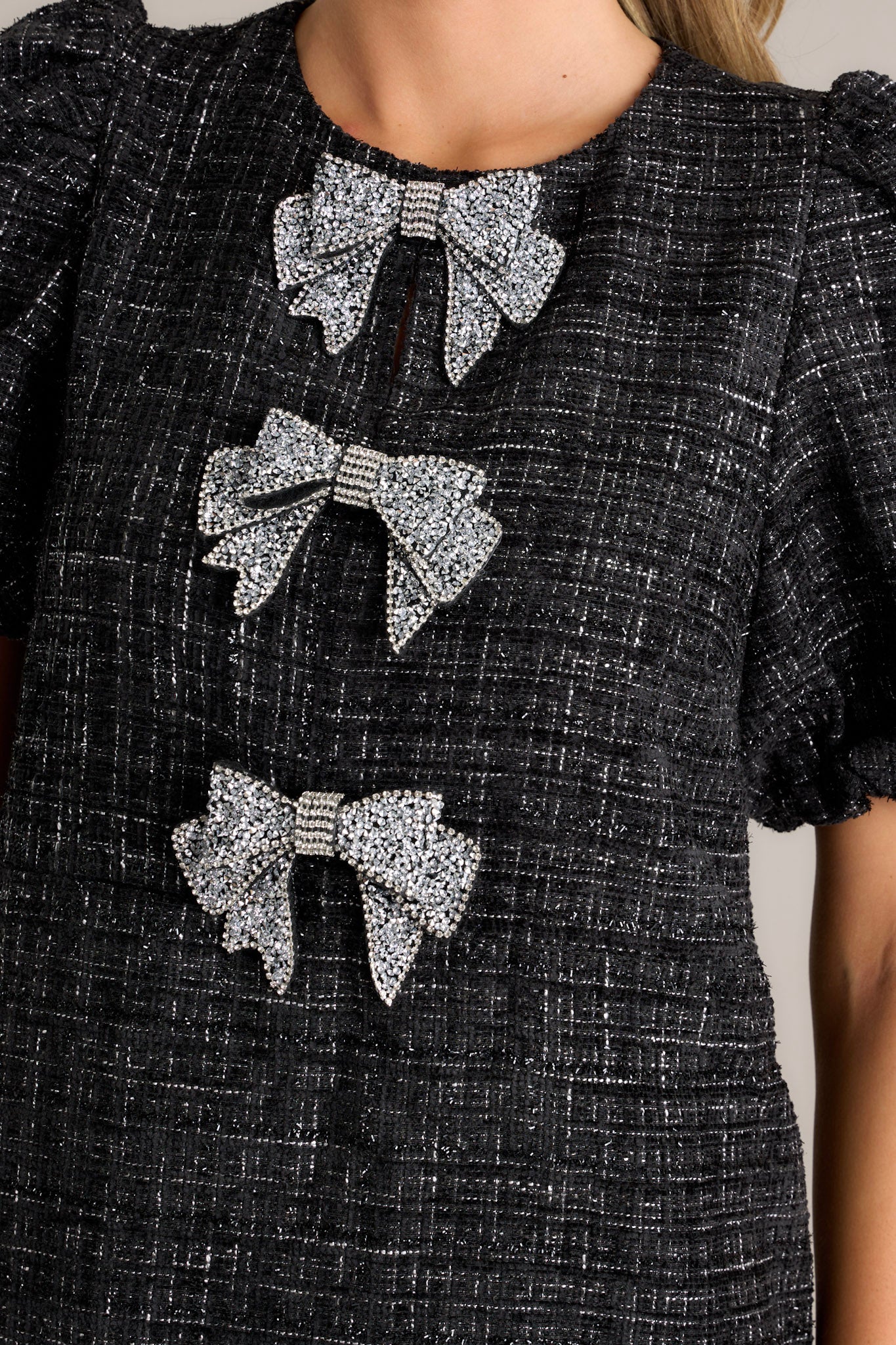 Close-up of the three large silver glitter bows on the black tweed dress.