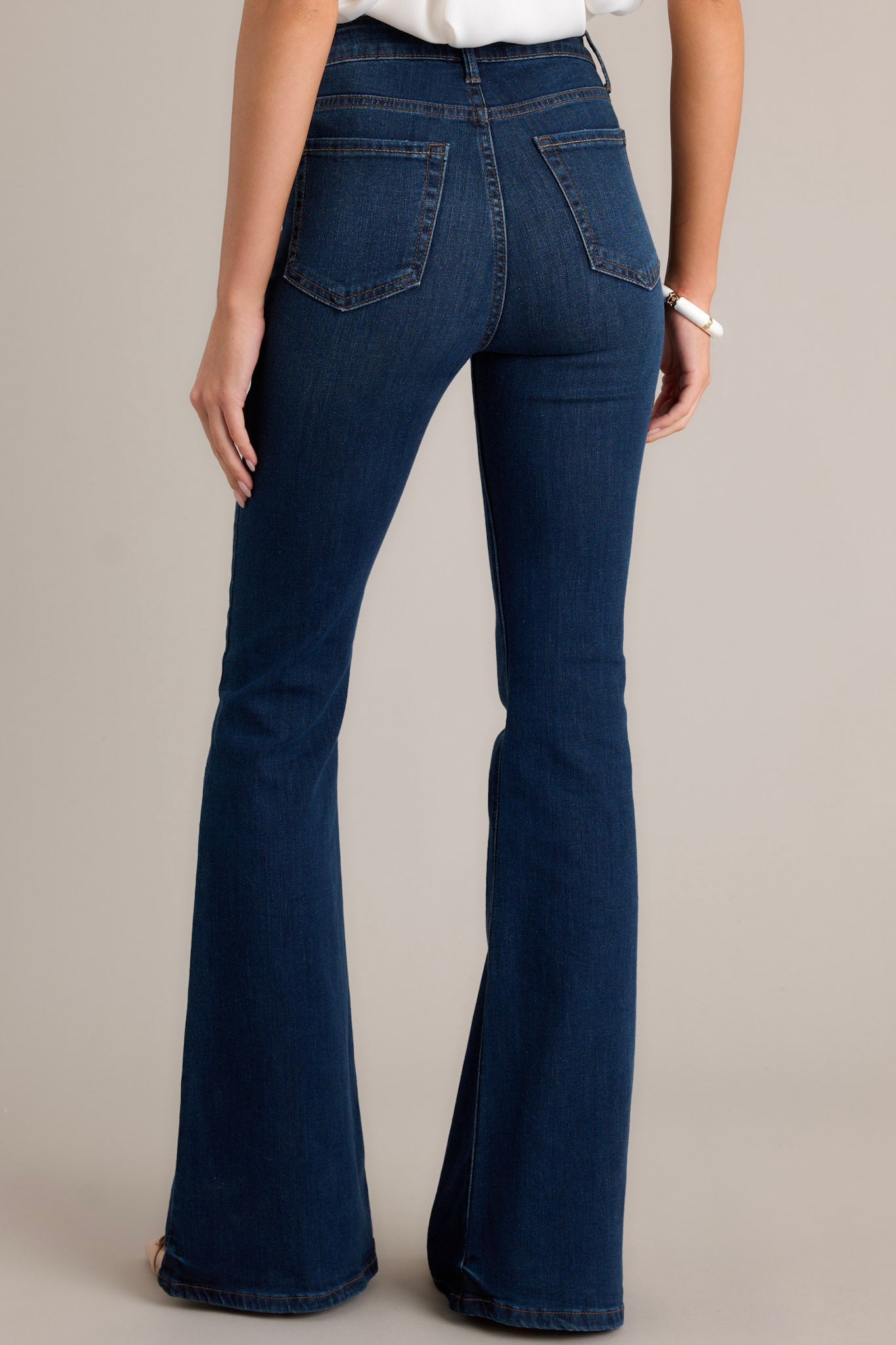 Back view of these jeans that feature a high waist fit, belt loops, zipper and button closure, functional pockets, and a bell bottom flare.