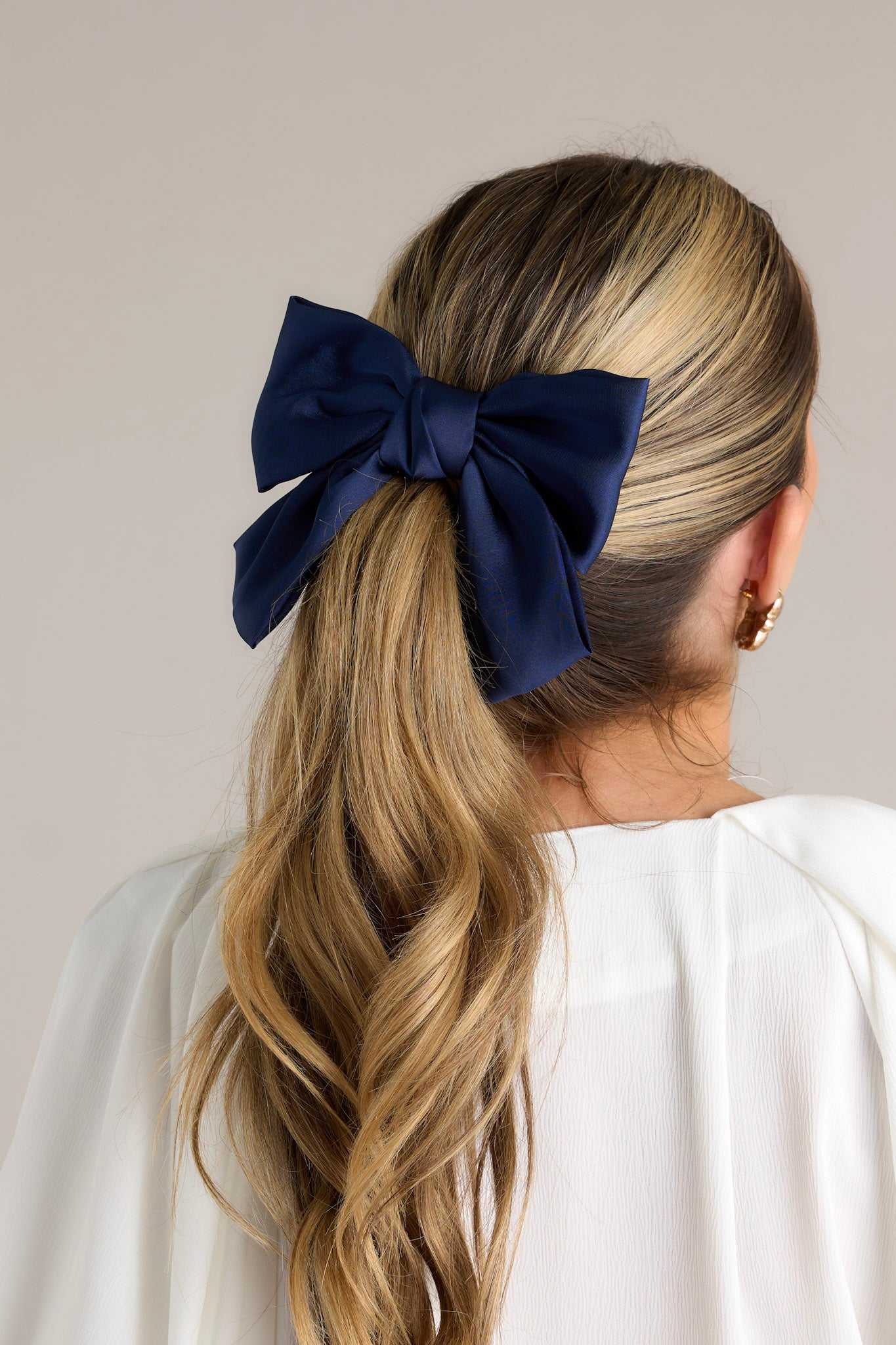 This hair clip features a classic navy bow and a barrette clip.