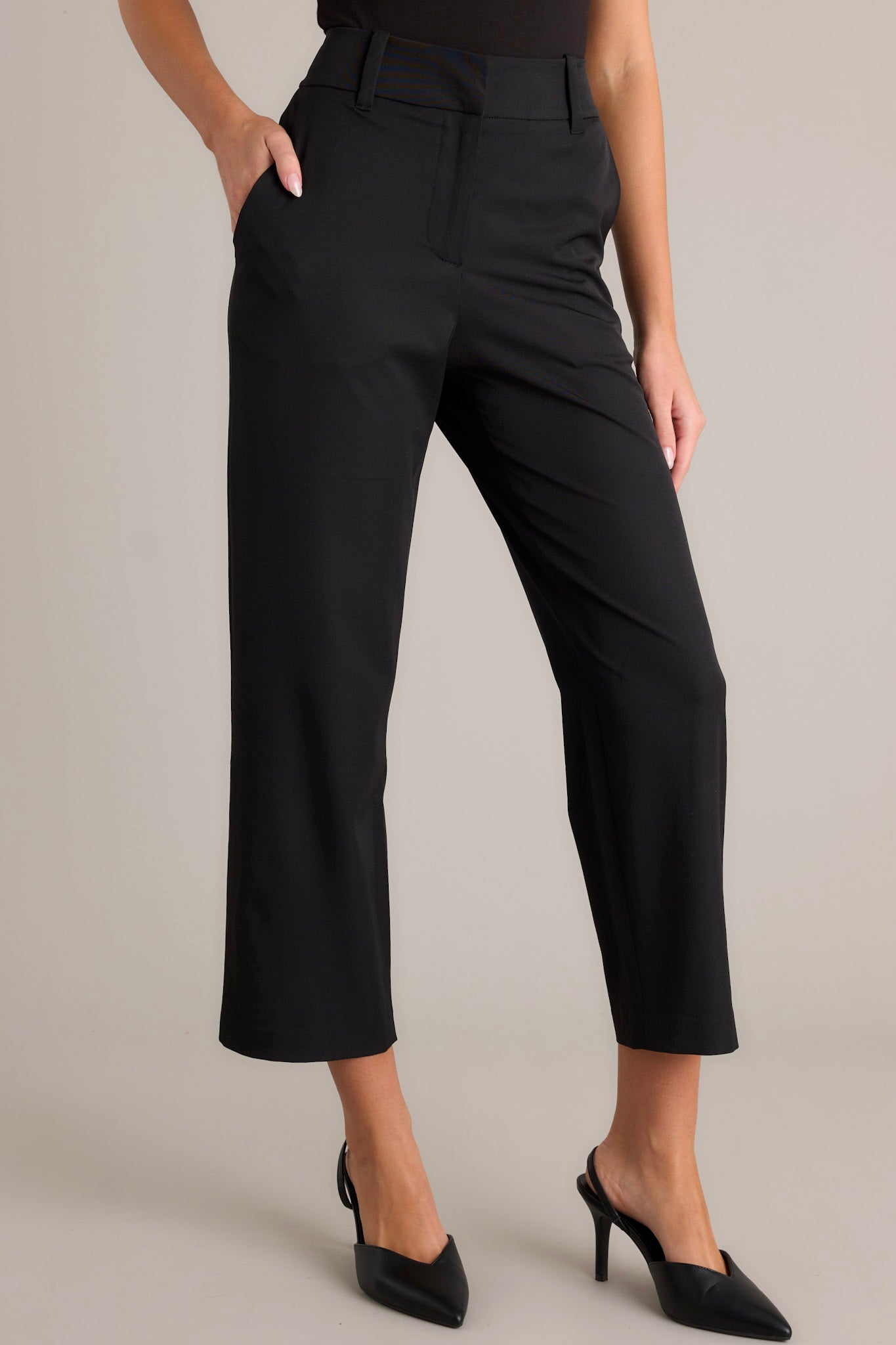 Close-up view of black straight leg pants showcasing the functional belt loops, zipper hook closure, and functional hip pockets.