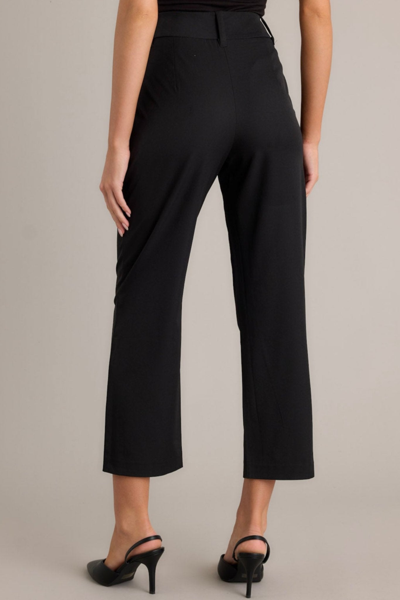 Back view of black straight leg pants with functional belt loops, styled with a black top and heels.