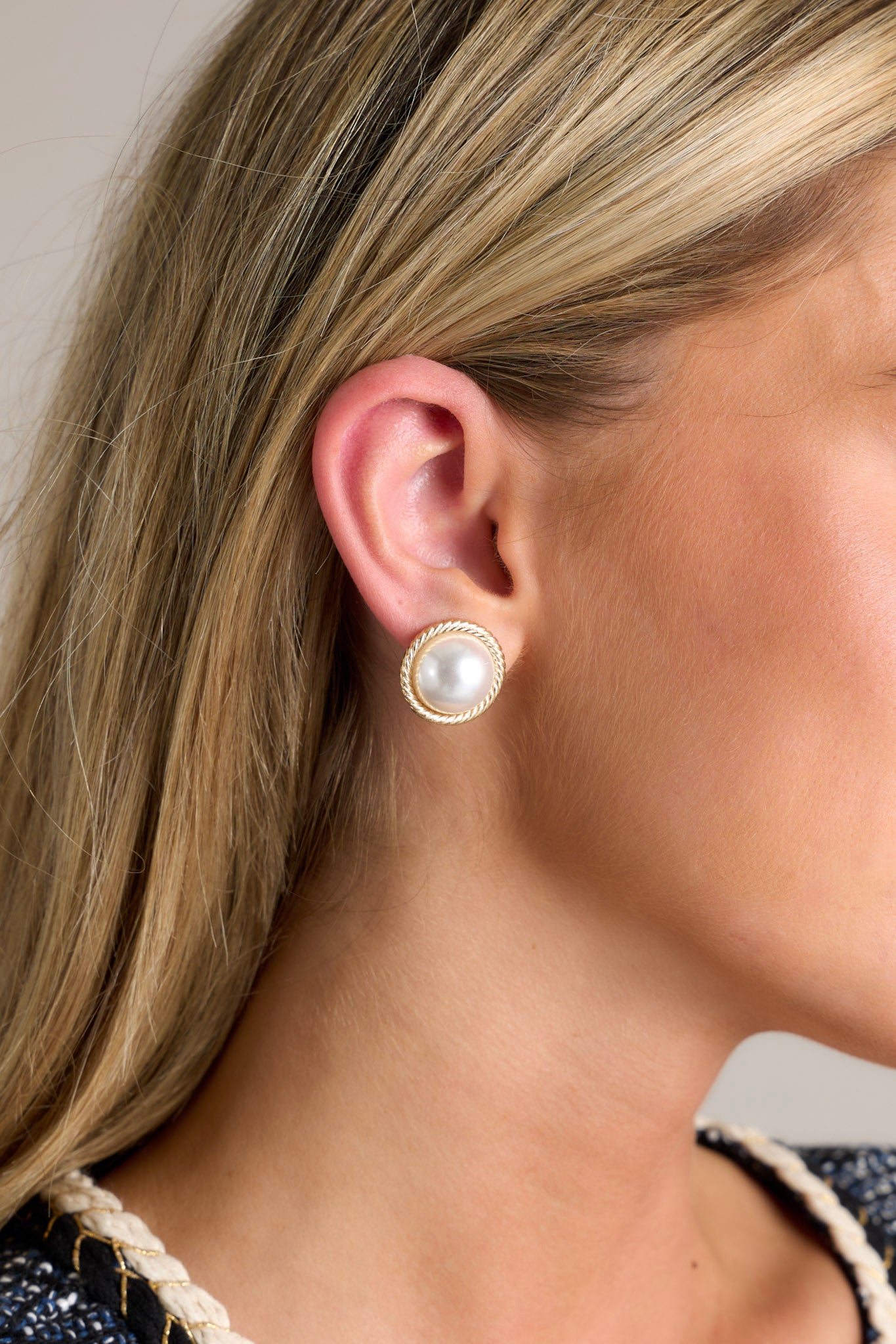 These pearl stud earrings feature a faux pearl, braided gold hardware wrapping the pearl and secure back postings.