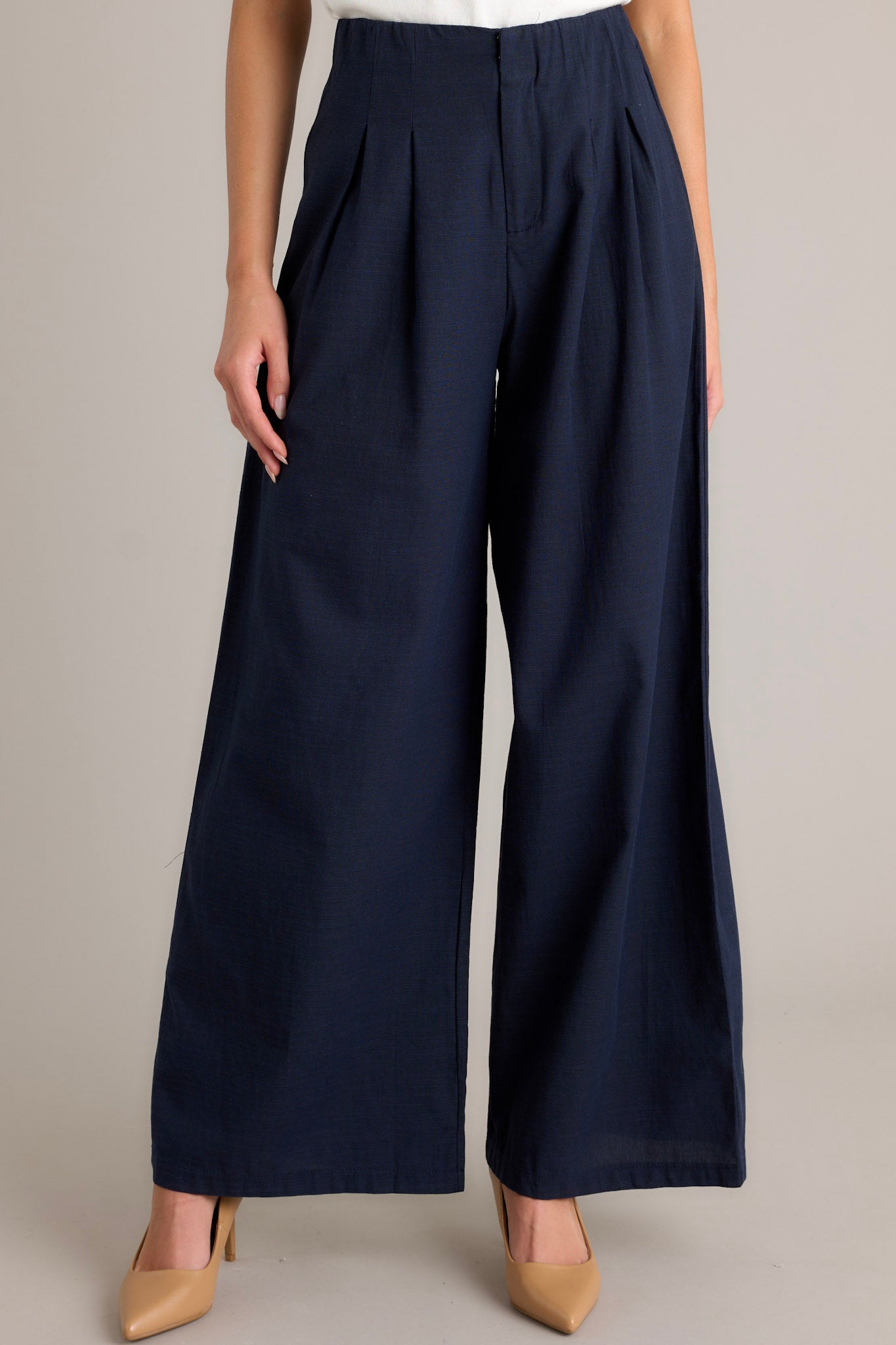 These navy straight leg pants feature a high waisted design, a button zipper closure, slight pleats, functional hip pockets and a straight leg.