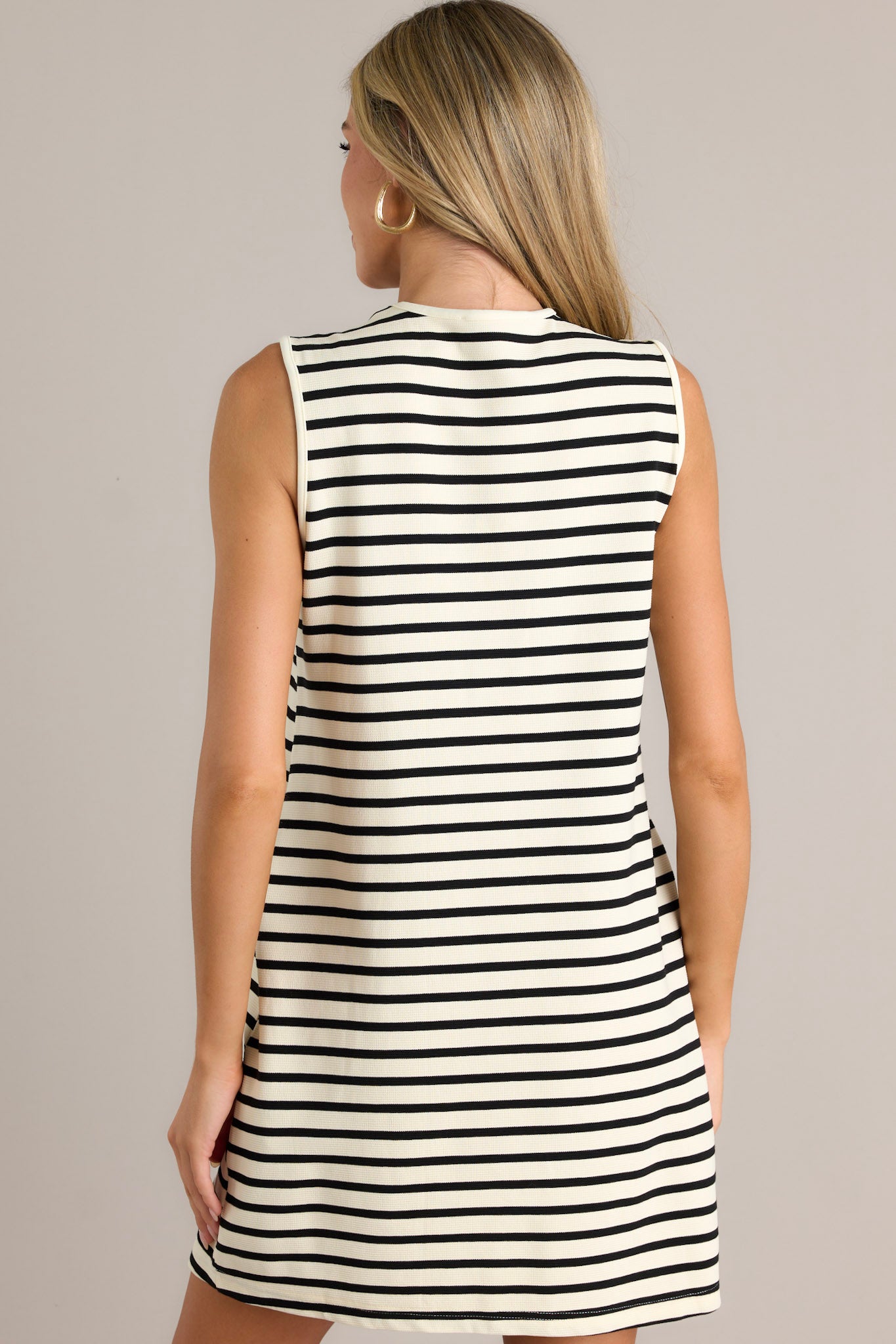 Back view of a sleeveless, black and ivory striped dress with a straight hemline.