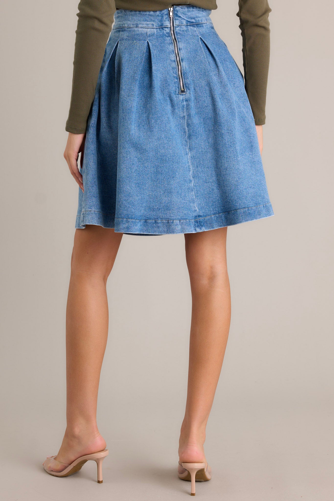 Back view of a denim skirt highlighting the back zipper closure and the high waisted design.