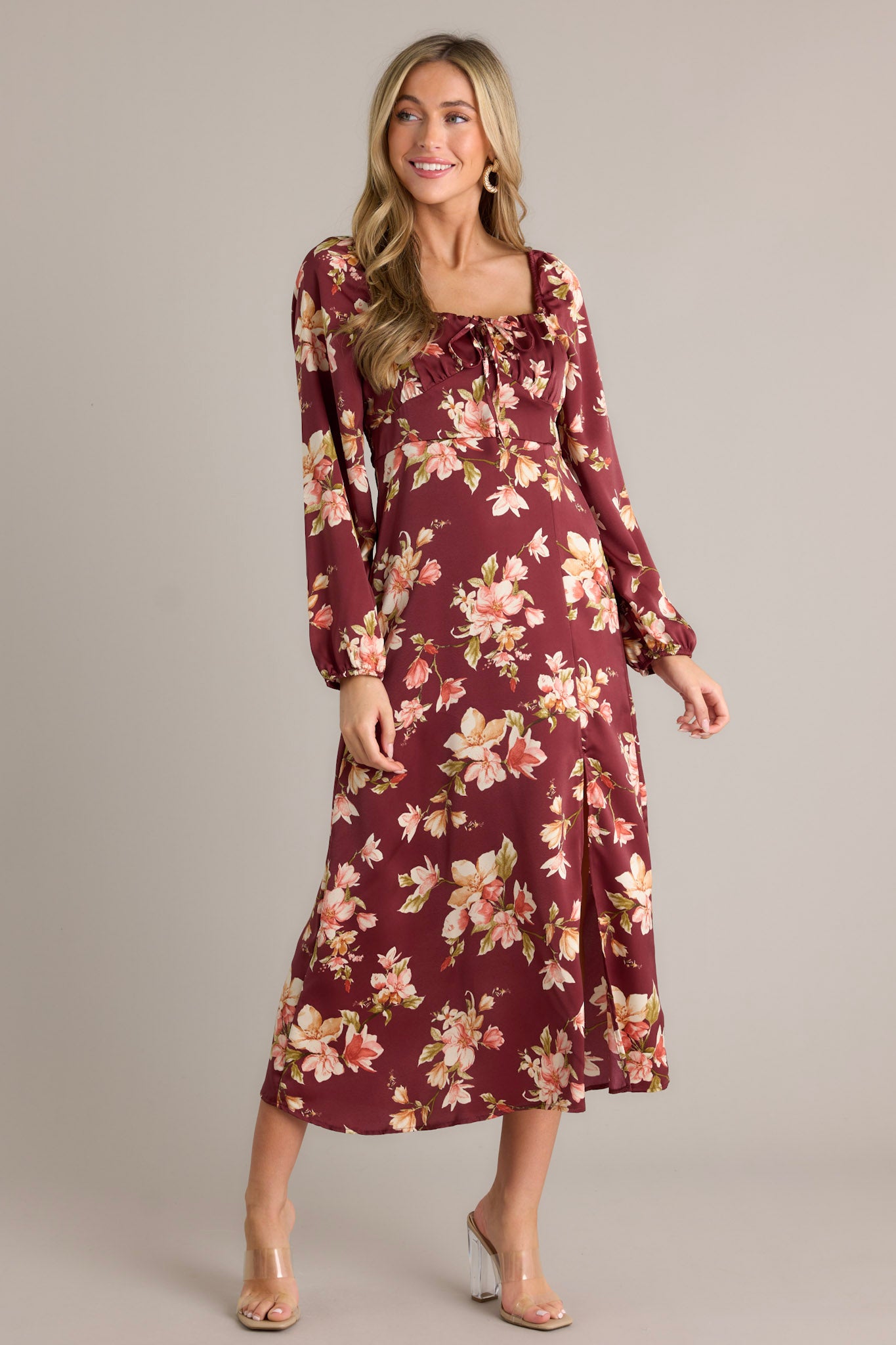 Front view of a burgundy floral dress with a square neckline, long sleeves, and a front slit.