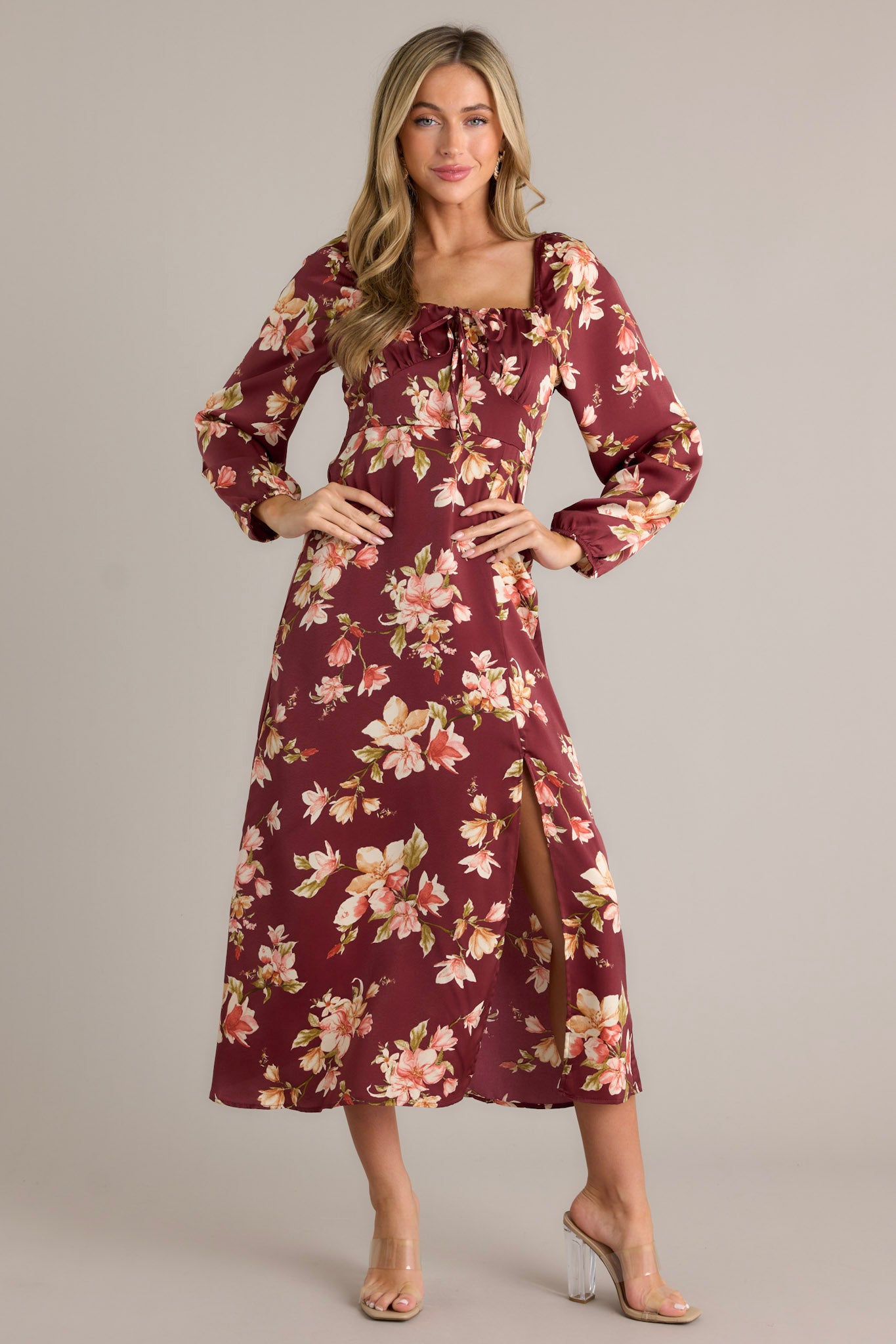 A burgundy dress with a floral pattern, square neckline, long sleeves, and front slit, shown from the front.